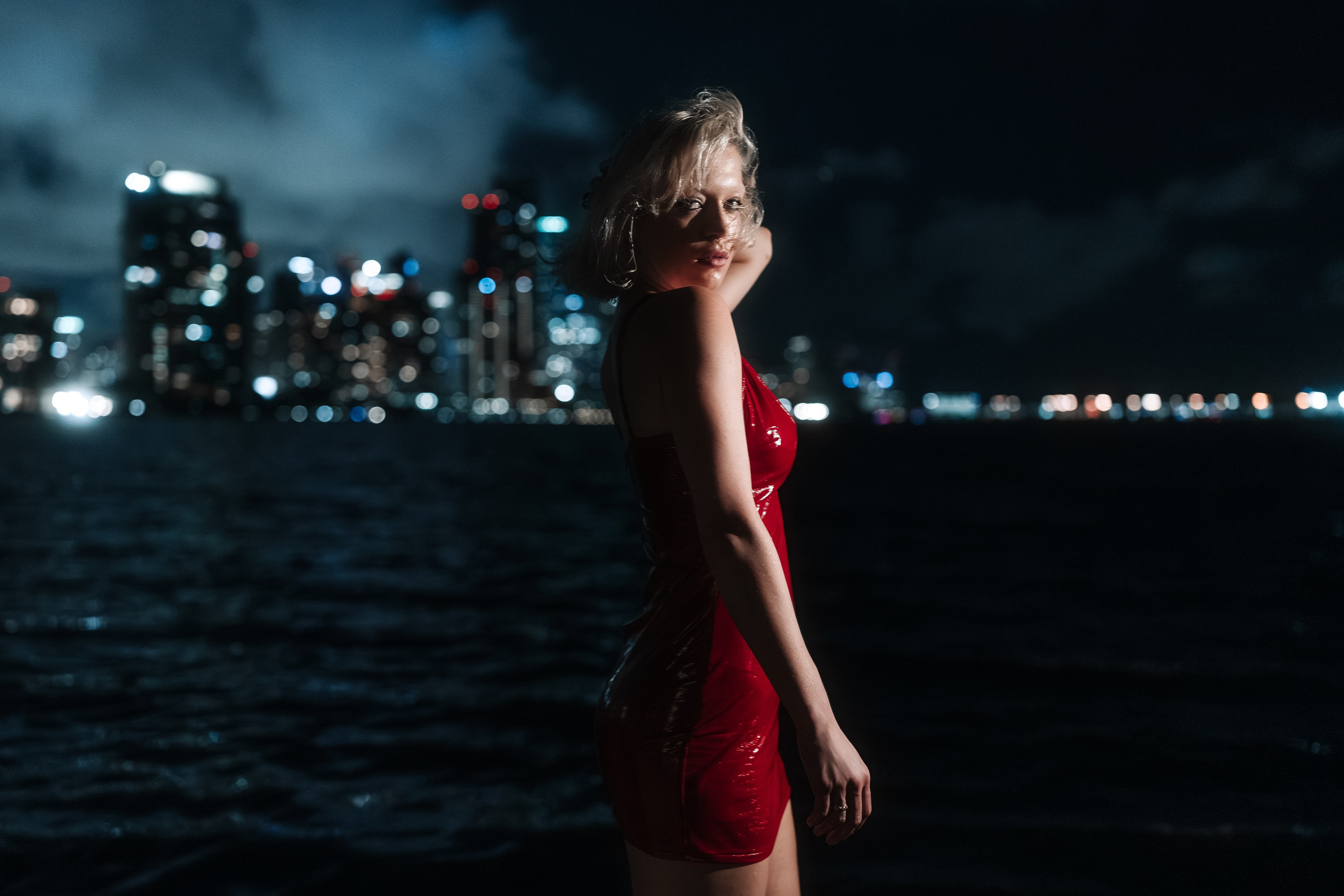 Bayfront photoshoot with a view of downtown Miami. The red dress adds drama, while lighting enhances skin and fabric detail.