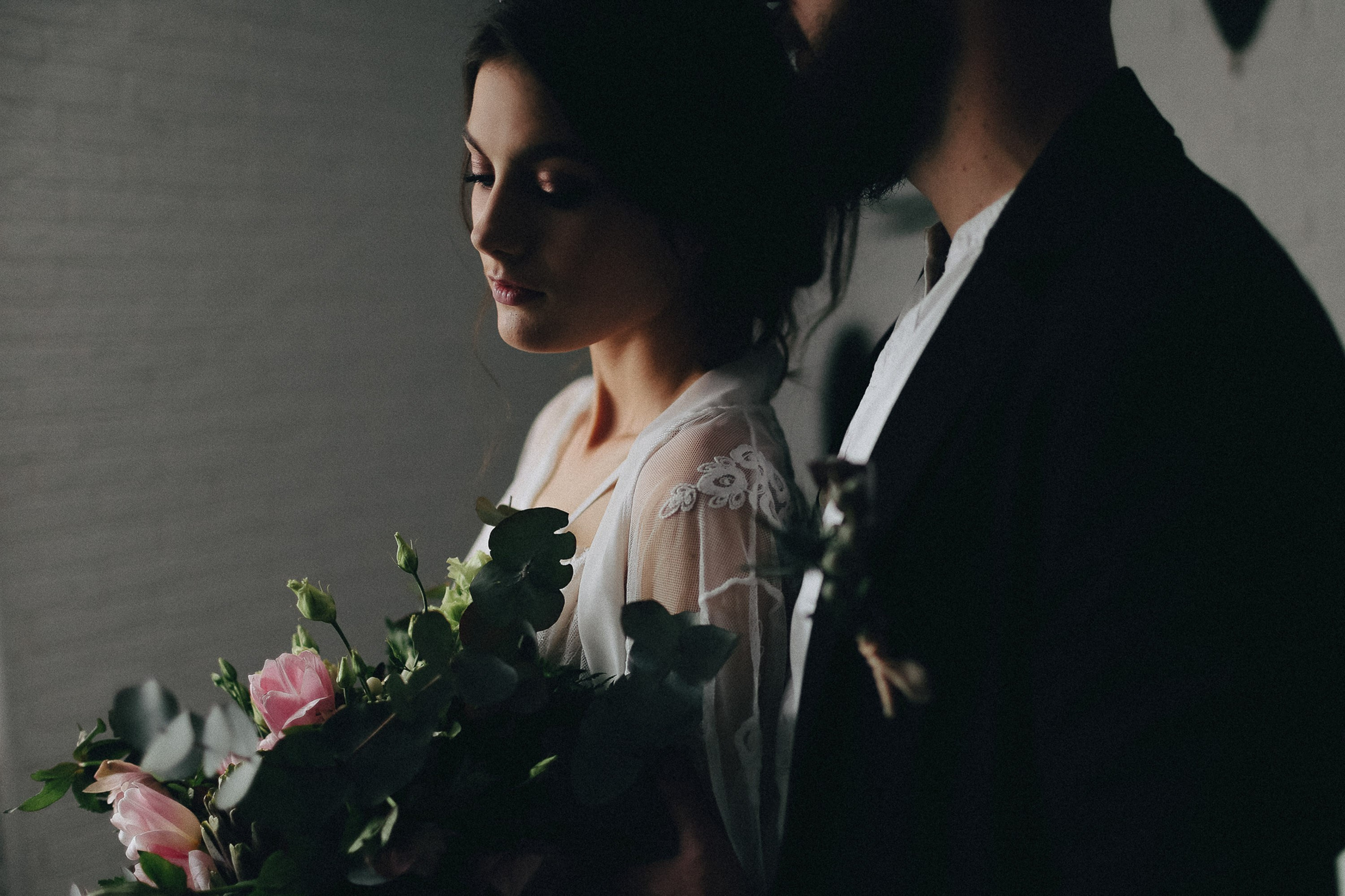 Bride and groom looking out window, intimate wedding preparation
