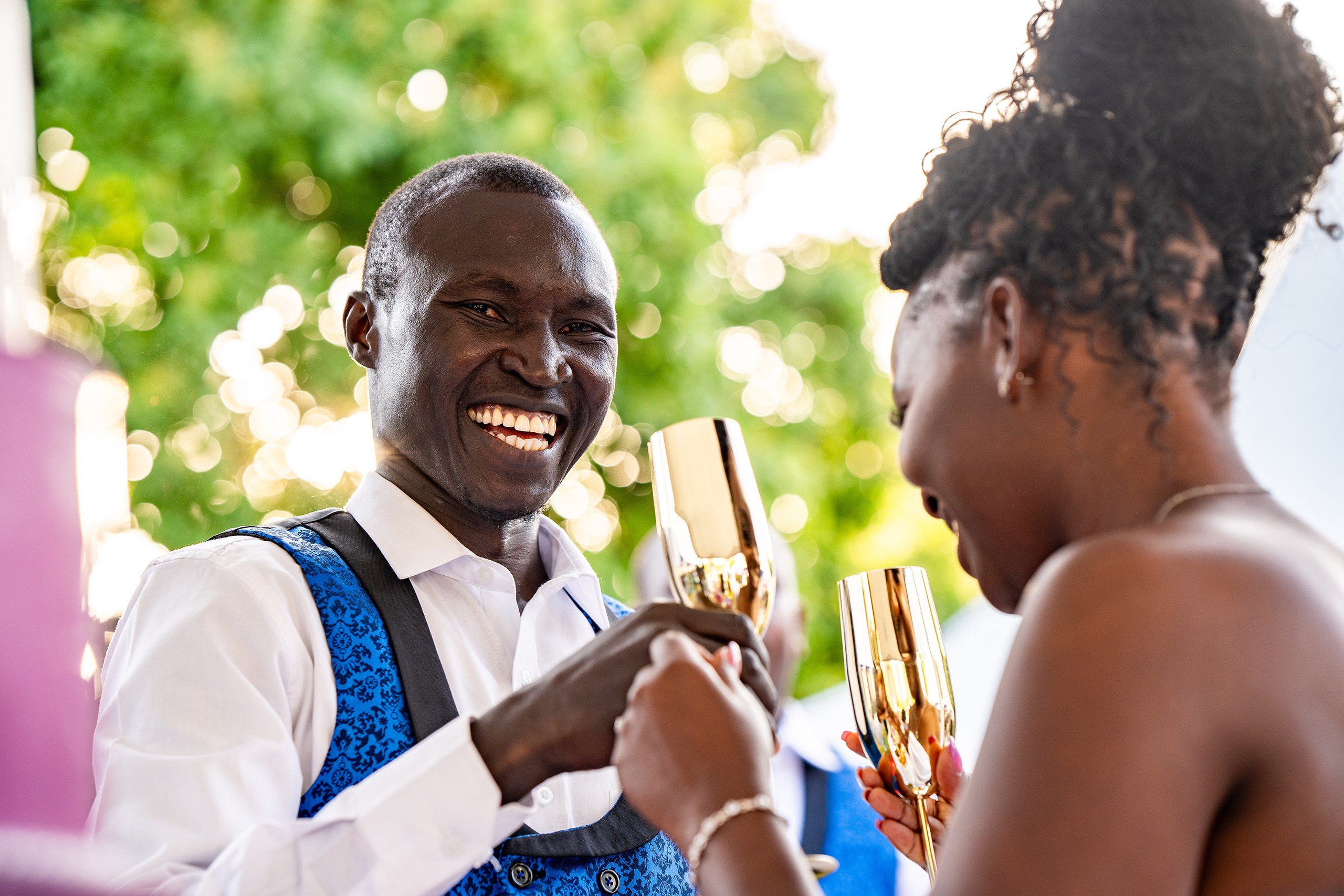 A close-up of a bride and groom toasting wine glasses cheerfully