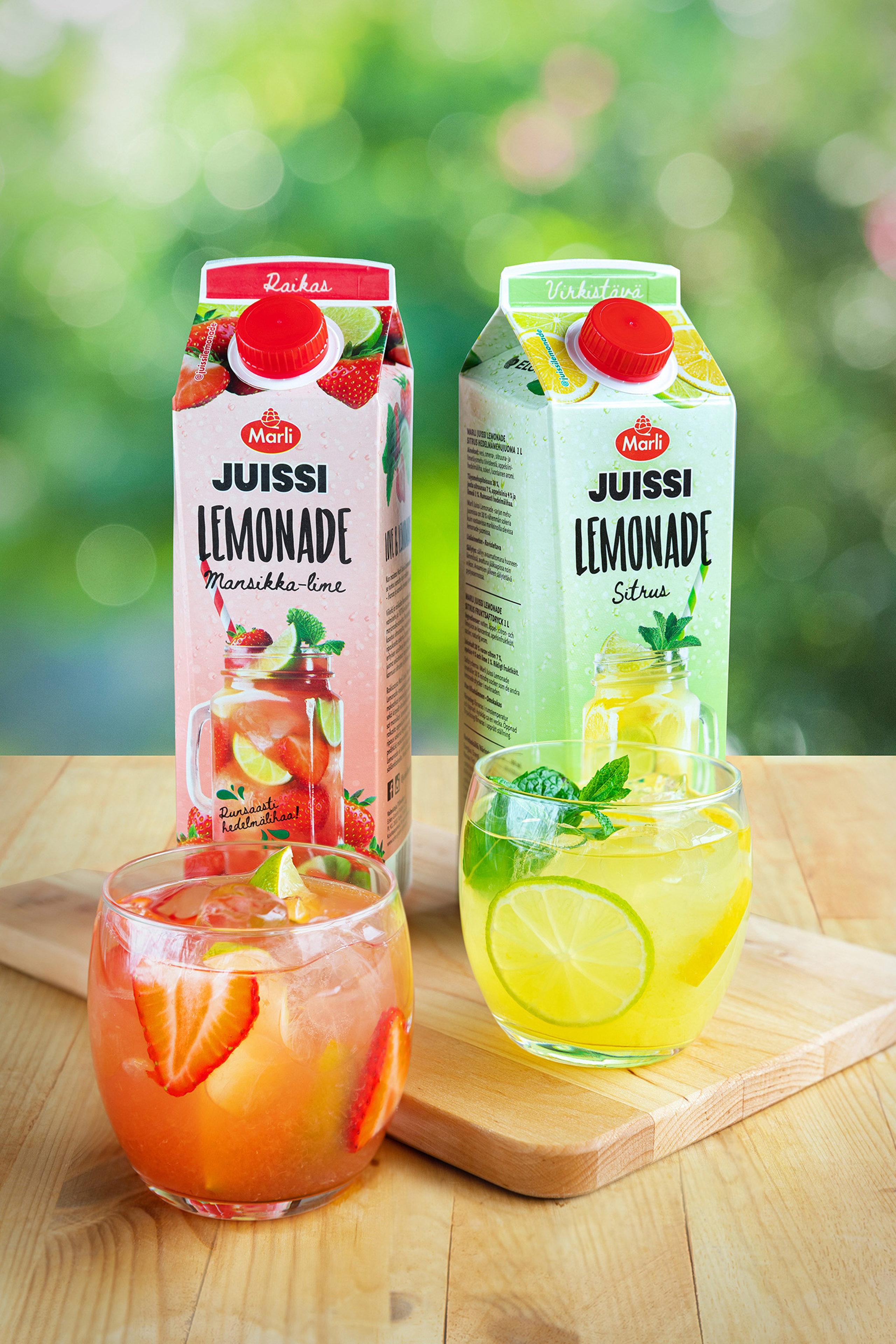 Two tetra packs with lemonade and two glasses of drinks with lemon and strawberries. Pictures for social media for the client.