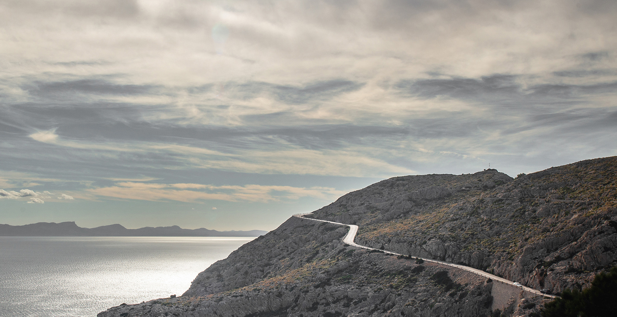 Seascape with a mountain road to the sun
