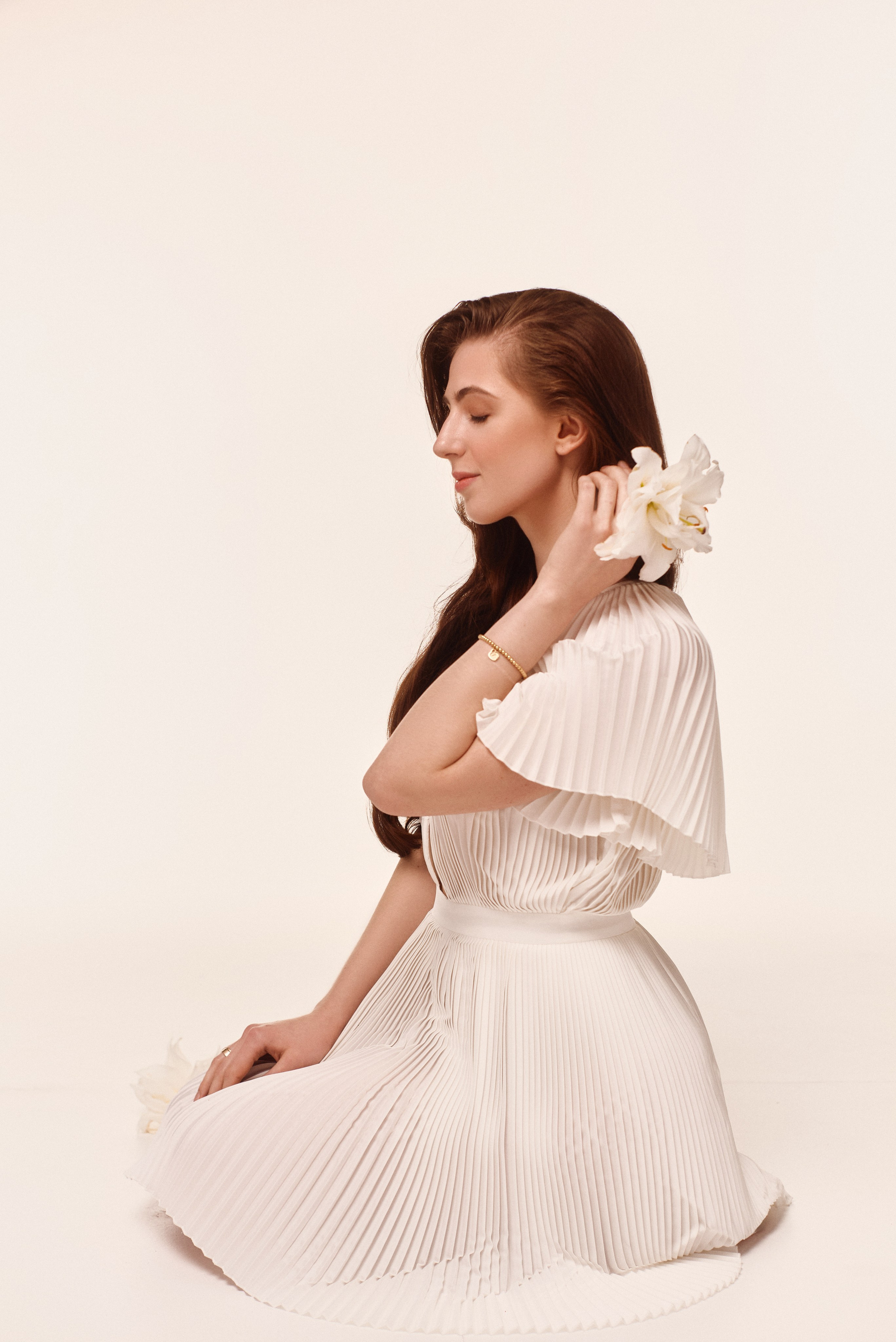 Subtelna sesja portretowa – kobieta w białej sukience z orchideą, delikatność i kobiecość w fotografii.