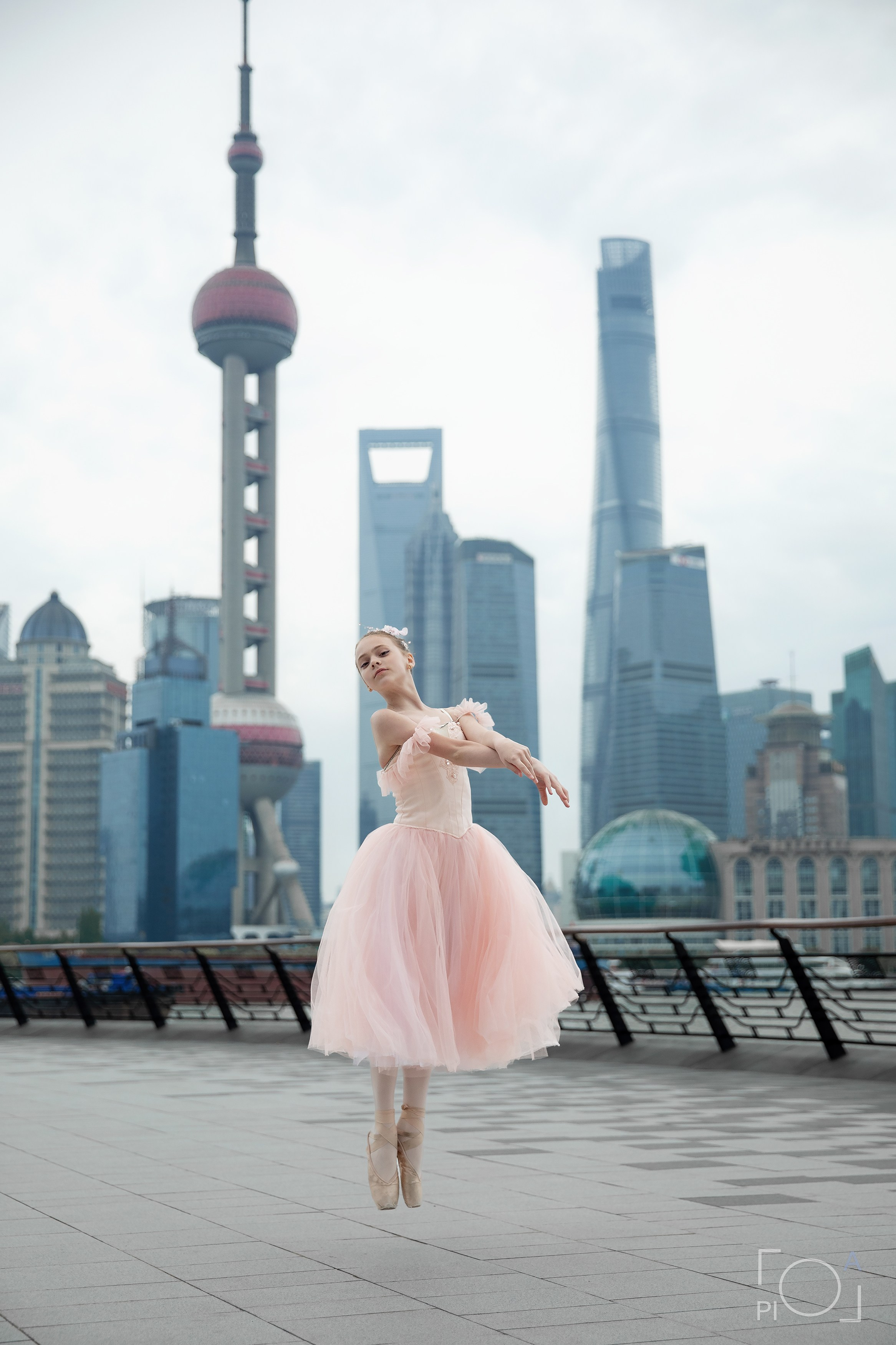 Фотосессия в Шанхае для девочки 11 лет. Маленькая балерина в розовом платье с пышной длинной пачкой, танцует на набережной в Шанхае с видом на Lujiazui