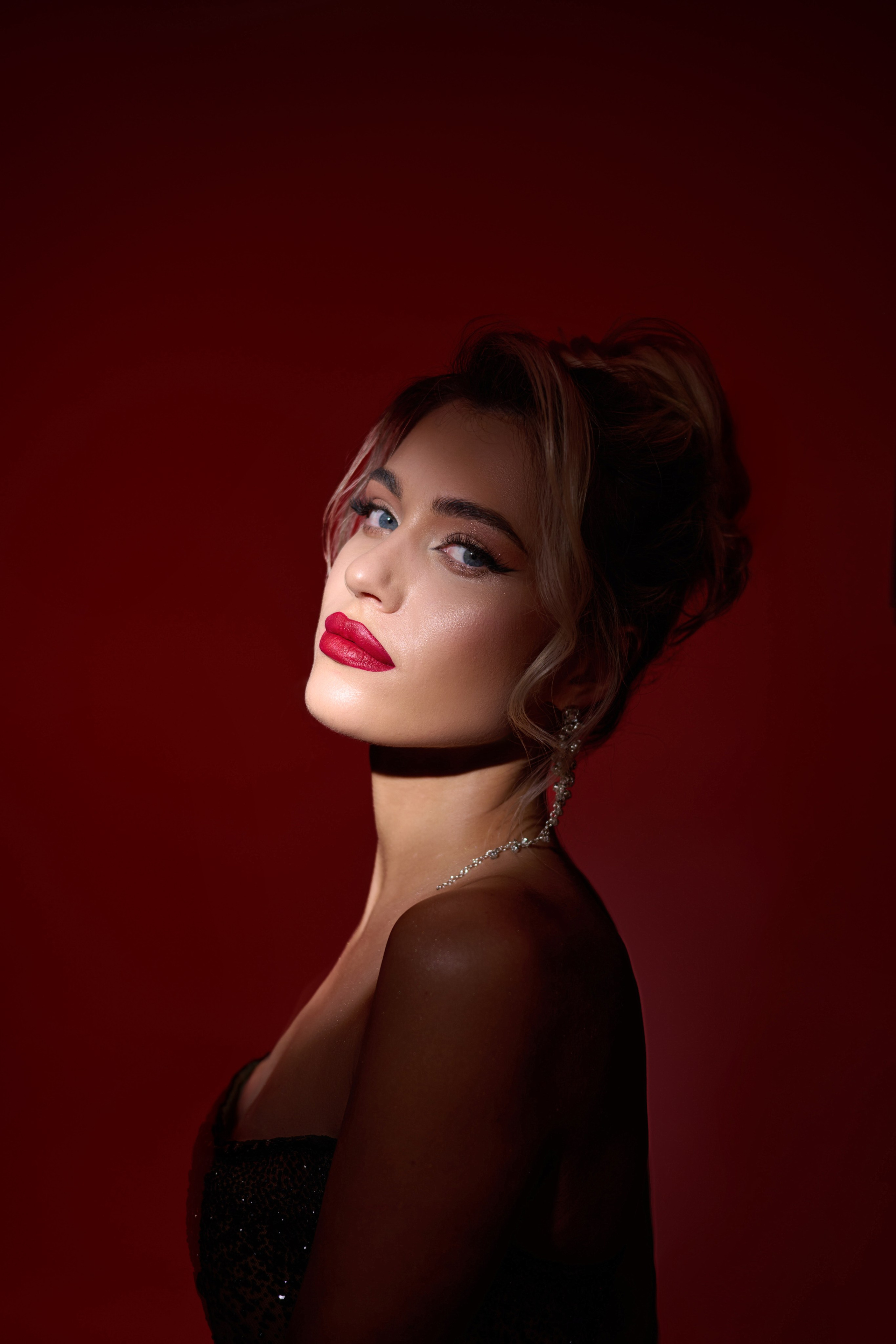 Intense close-up portrait of woman in white couture dress with red dramatic studio lighting