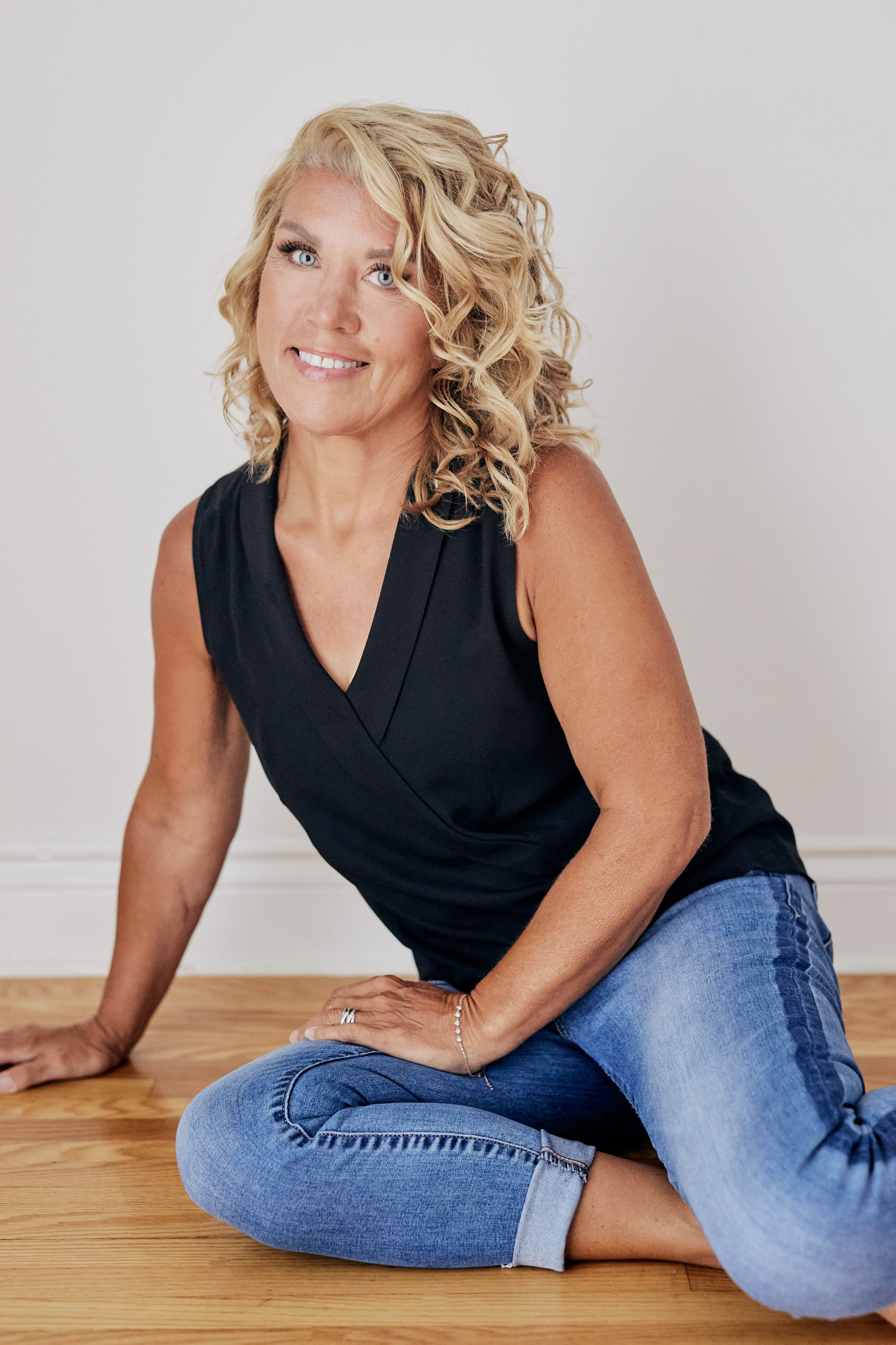 mature woman headshot sitting on floor smiling 
