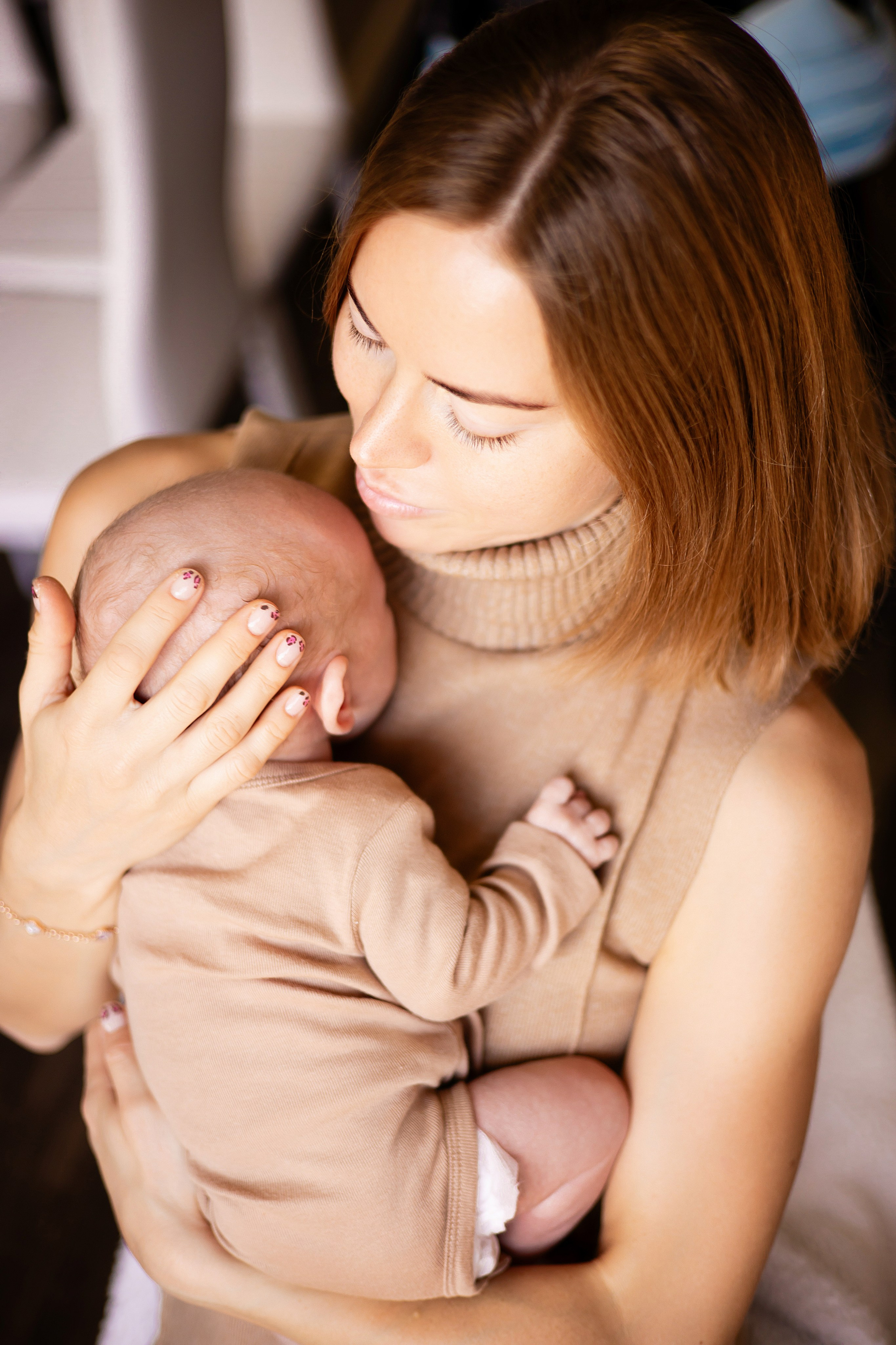 Mother kissing newborn in a cozy home environment