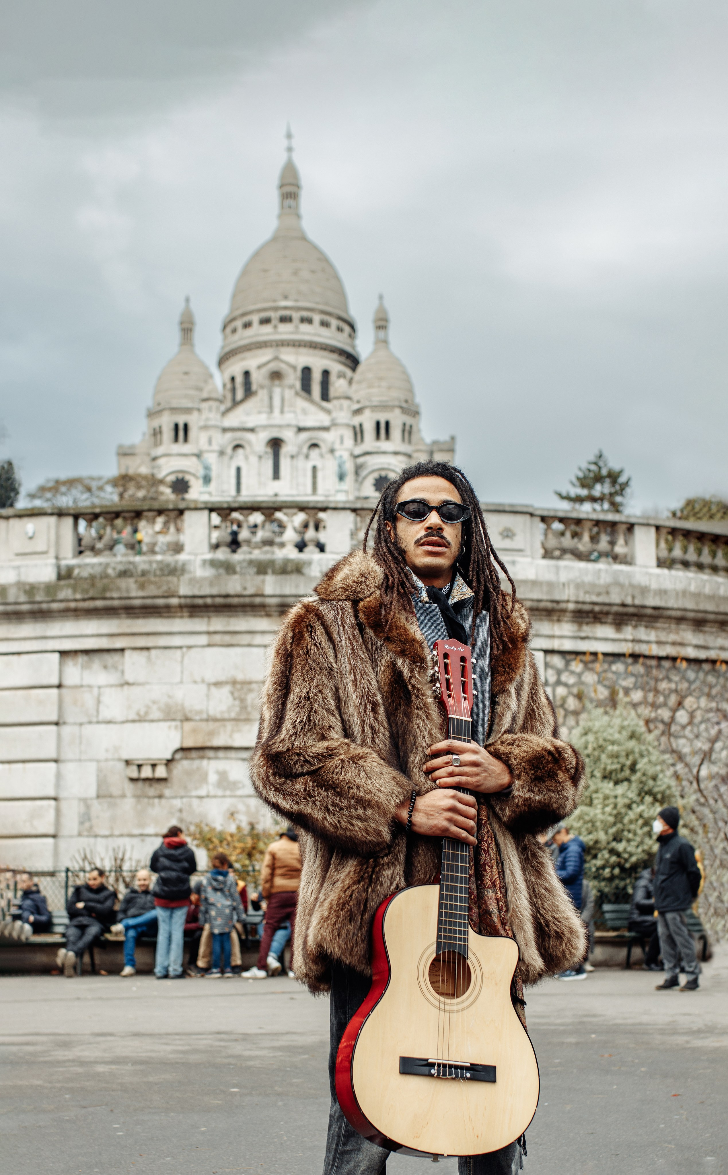Музыант с гитарой на фоне базилики Сакре-Кёр на Монмартре в Париже