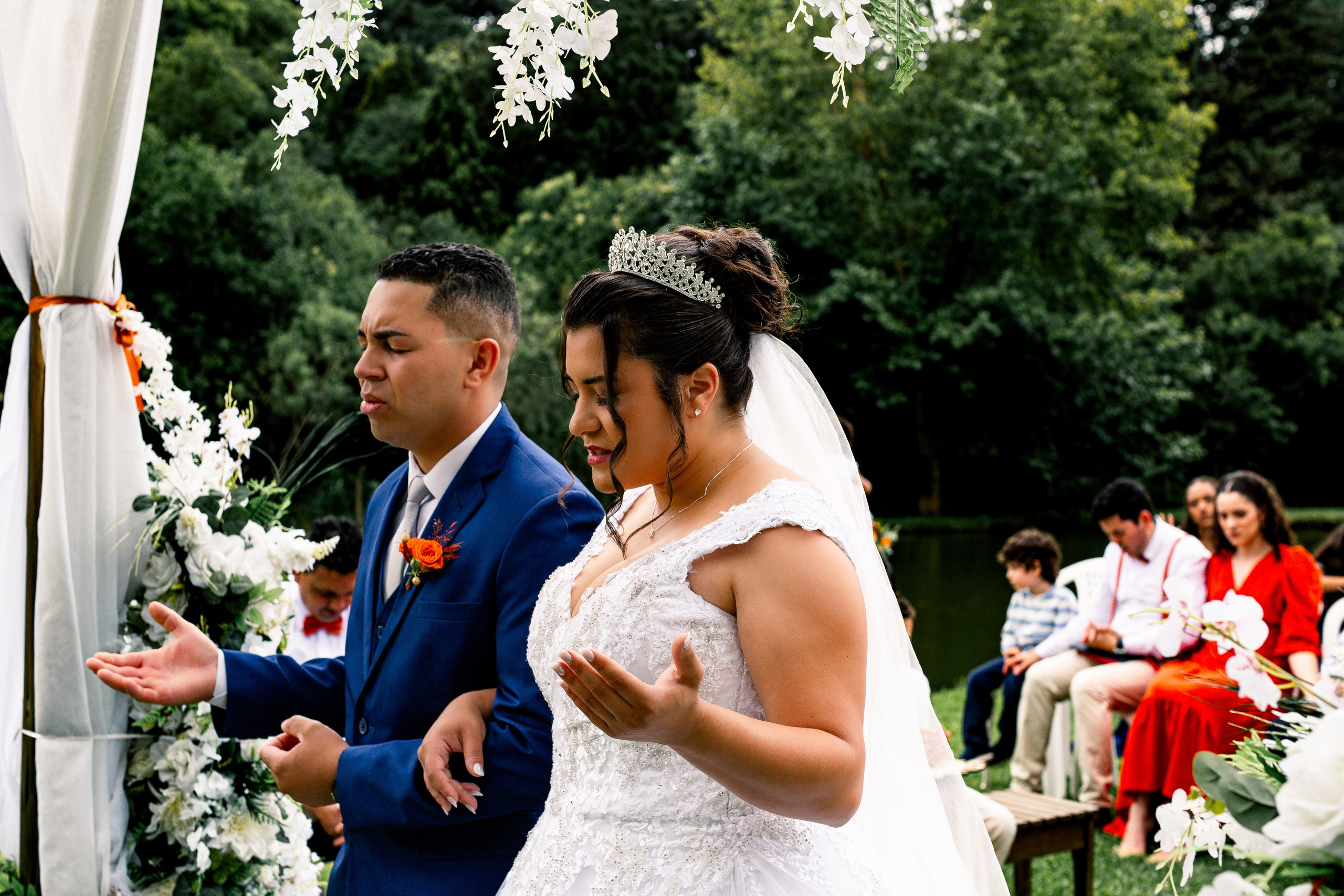 Noivos em oração de mãos dadas no altar, fotografia de casamento com fé e conexão espiritual.