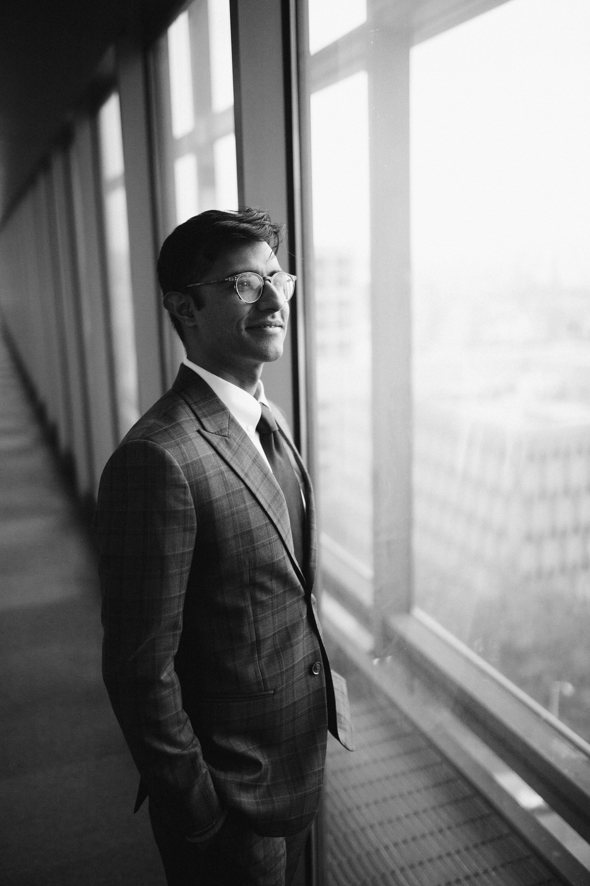 Groom looking out window, thoughtful wedding moment