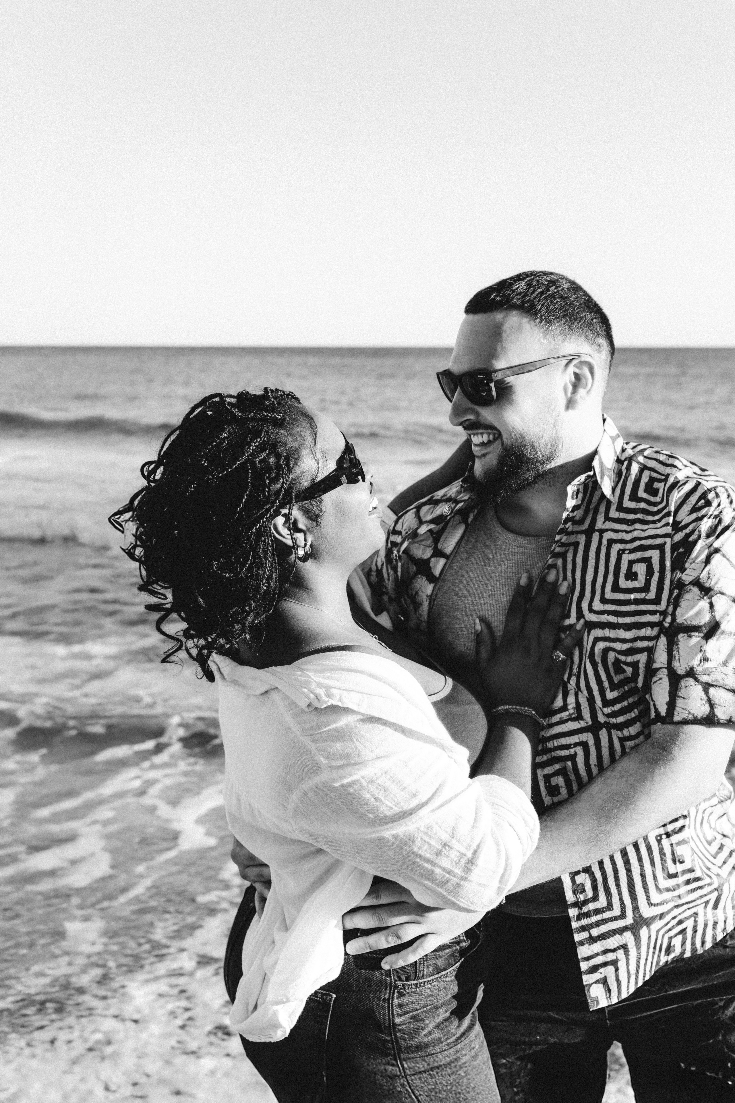 Momento espontáneo en la playa durante una sesión de fotos de historia de amor en Valencia, España — risas, conexión y encanto mediterráneo capturados en blanco y negro. Ideal para parejas que buscan sesiones de fotos románticas y naturales en Valencia y en toda España.