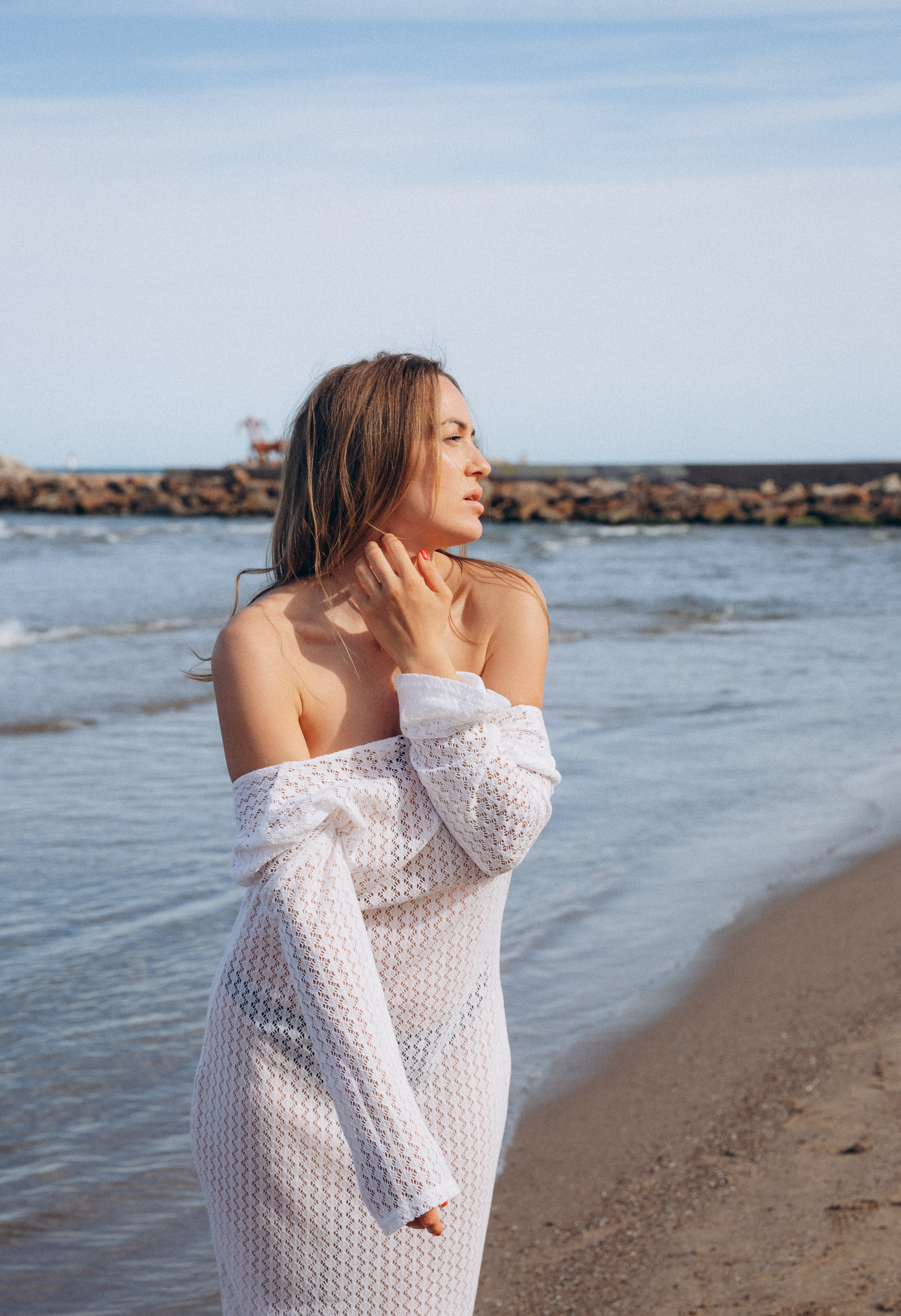 Чувственный пляжный портрет женщины в белом фактурном платье у моря в Кальпе, Испания — вдохновение для элегантных и эмоциональных фотосессий на берегу в Коста-Бланке и средиземноморской Испании.