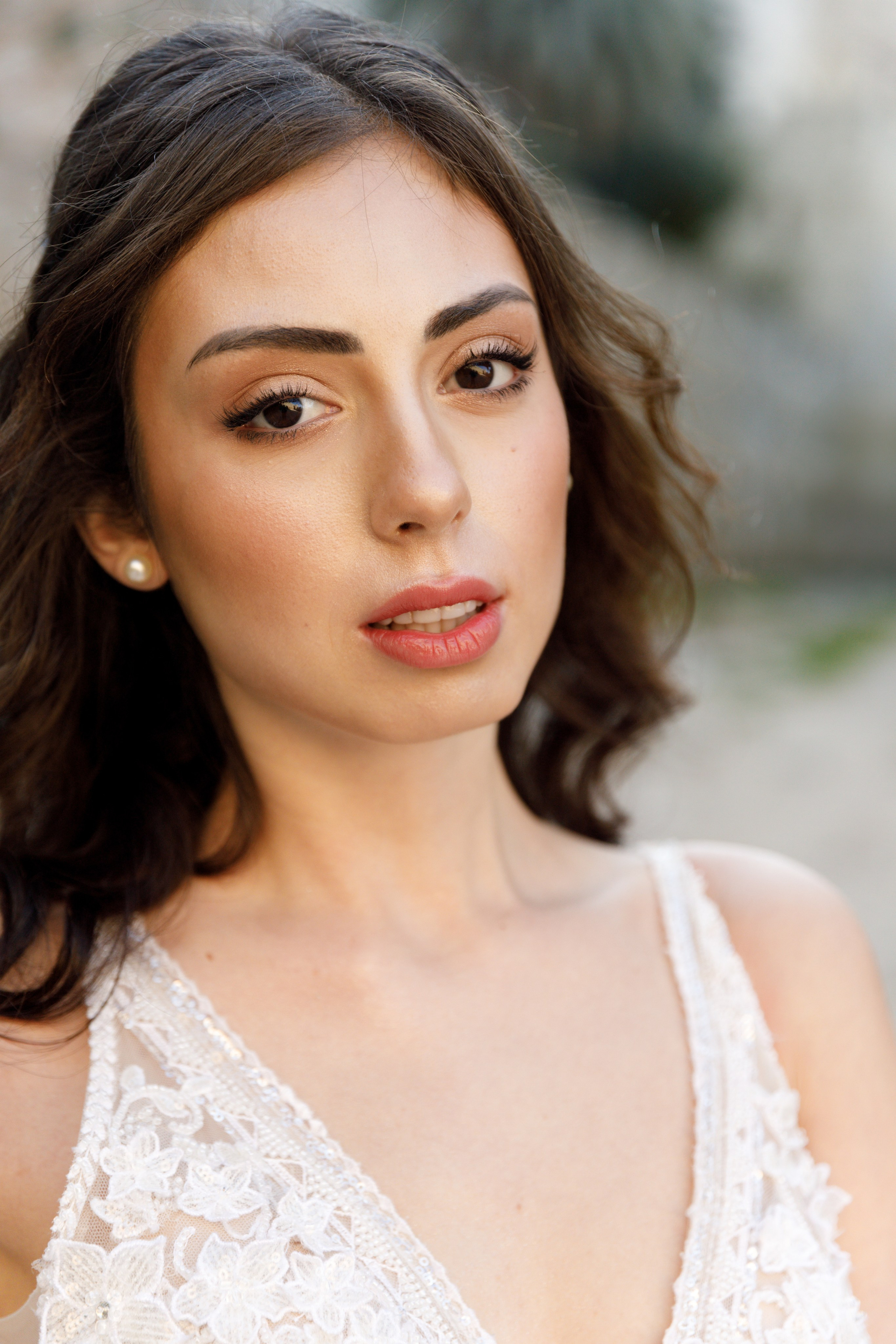 A stunning bride gazes thoughtfully in the enchanting alleys of Rhodes' Old Town, her flowing wedding dress complementing the rustic charm of the cobblestone streets and ancient architecture. The editorial-style portrait captures her poise and the romantic atmosphere of the medieval surroundings, bathed in warm, golden light.
