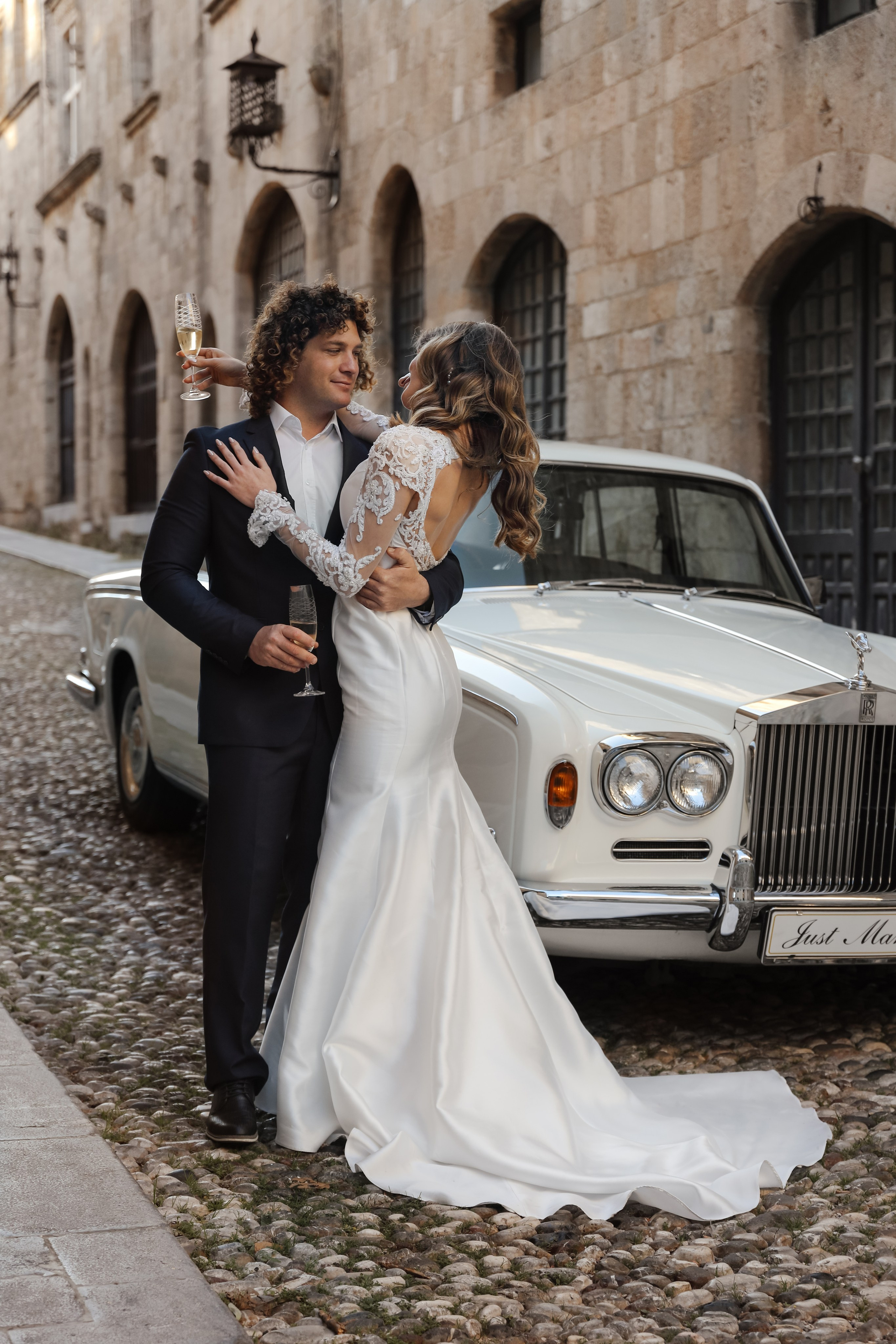 A bride and groom next to Rolls Royce in old town of Rhodes island, Greece