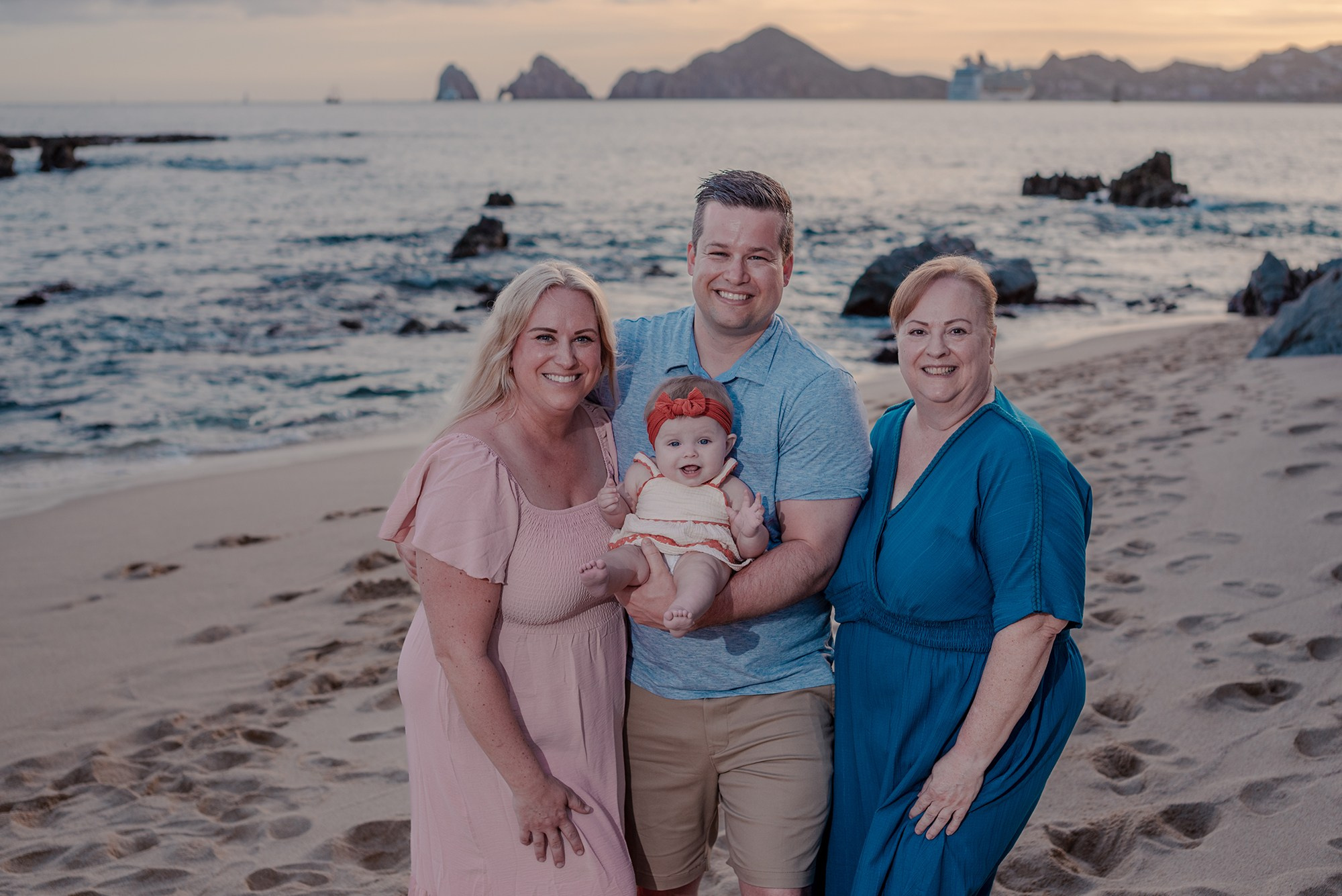 Three generations of family photographed together on the beach at Playa Monumentos Cabo San Lucas during golden hour
