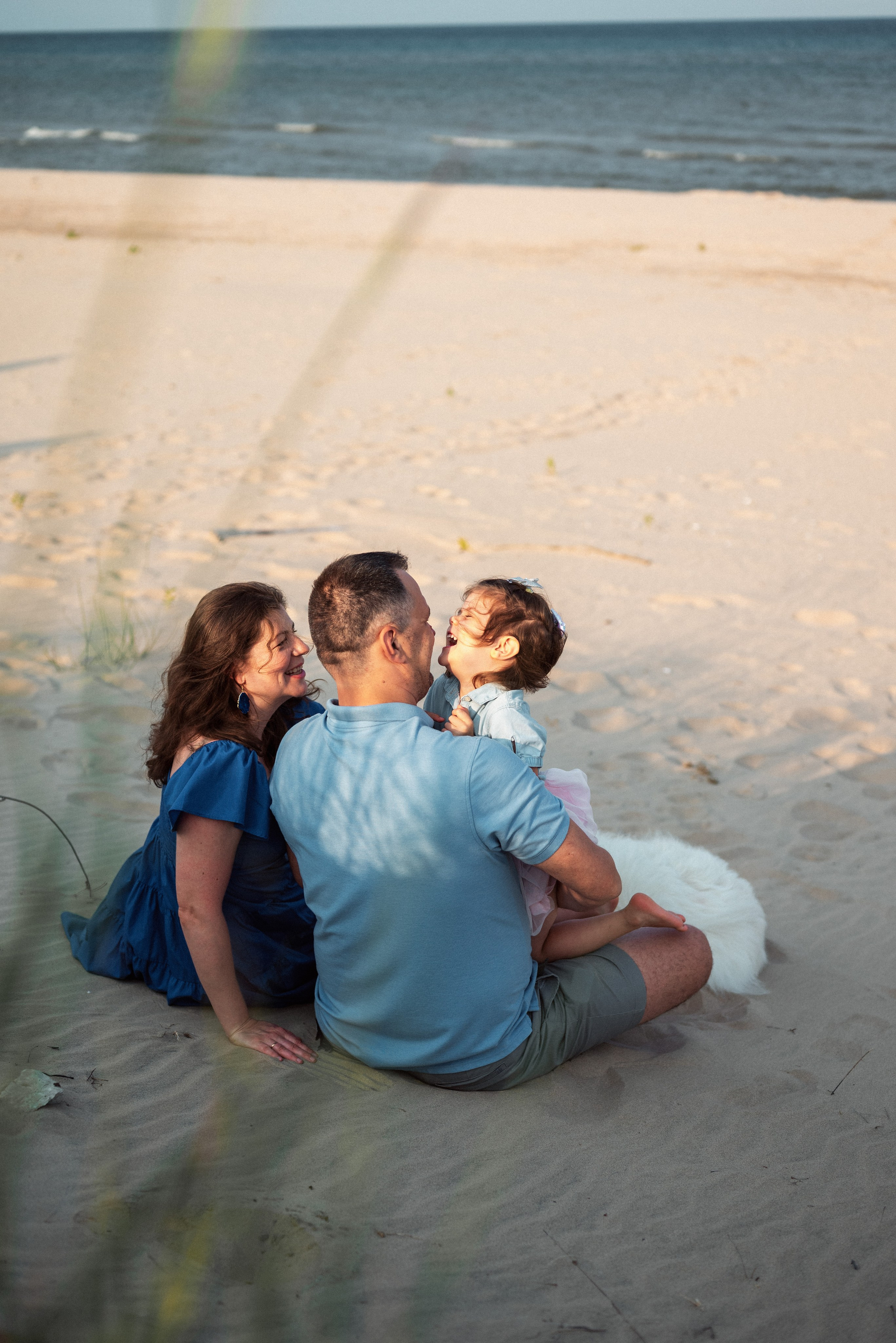 Family enjoying a playful beach photoshoot in Green Bay, Wisconsin. Perfect for capturing the warmth and joy of family bonds by the water.