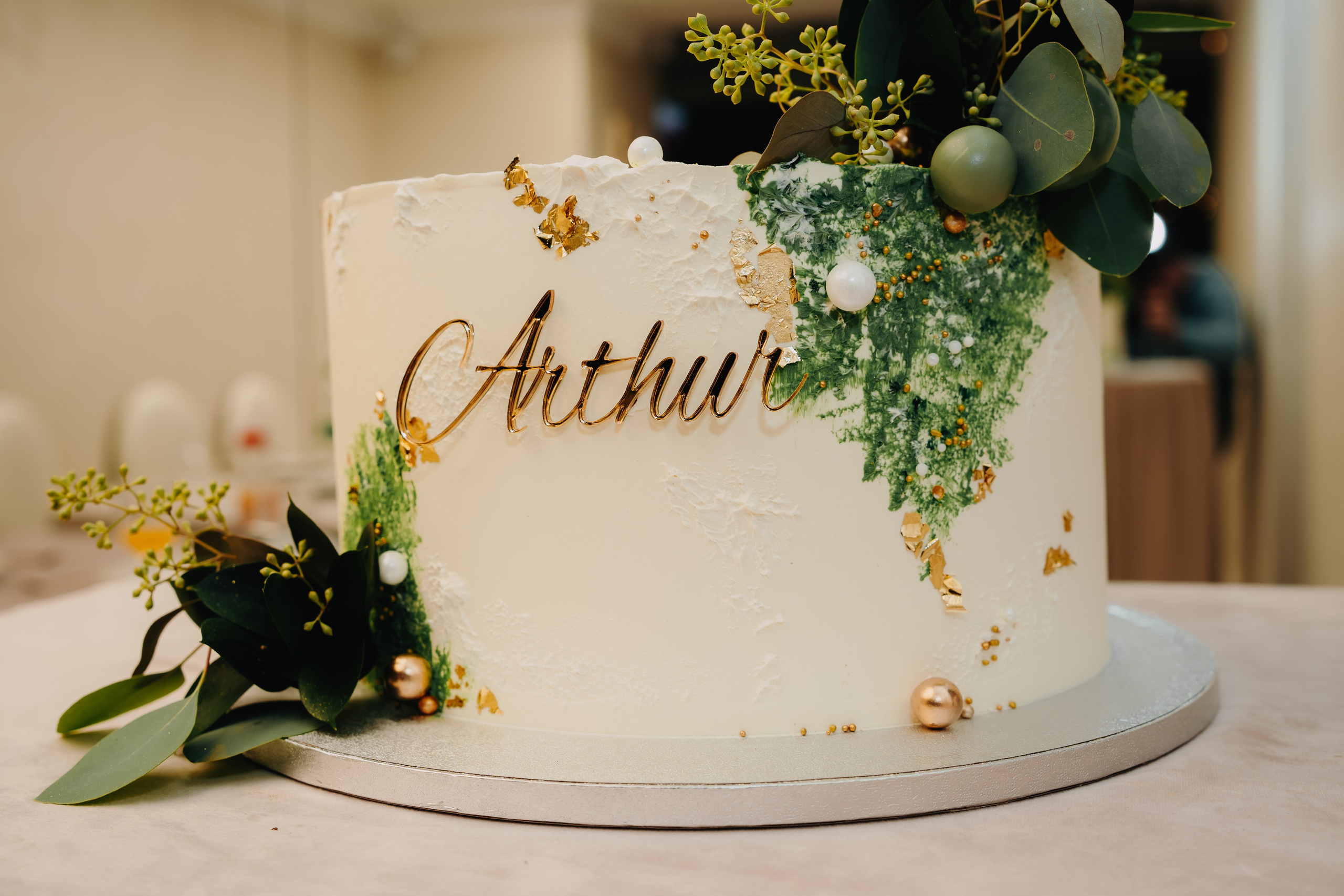 Close-up artistic pe inscripția sau decorația principală de pe tortul de botez al lui Arthur Mihail (ex: numele "Arthur", o temă specifică). Detaliu personalizat și dulce al serii.