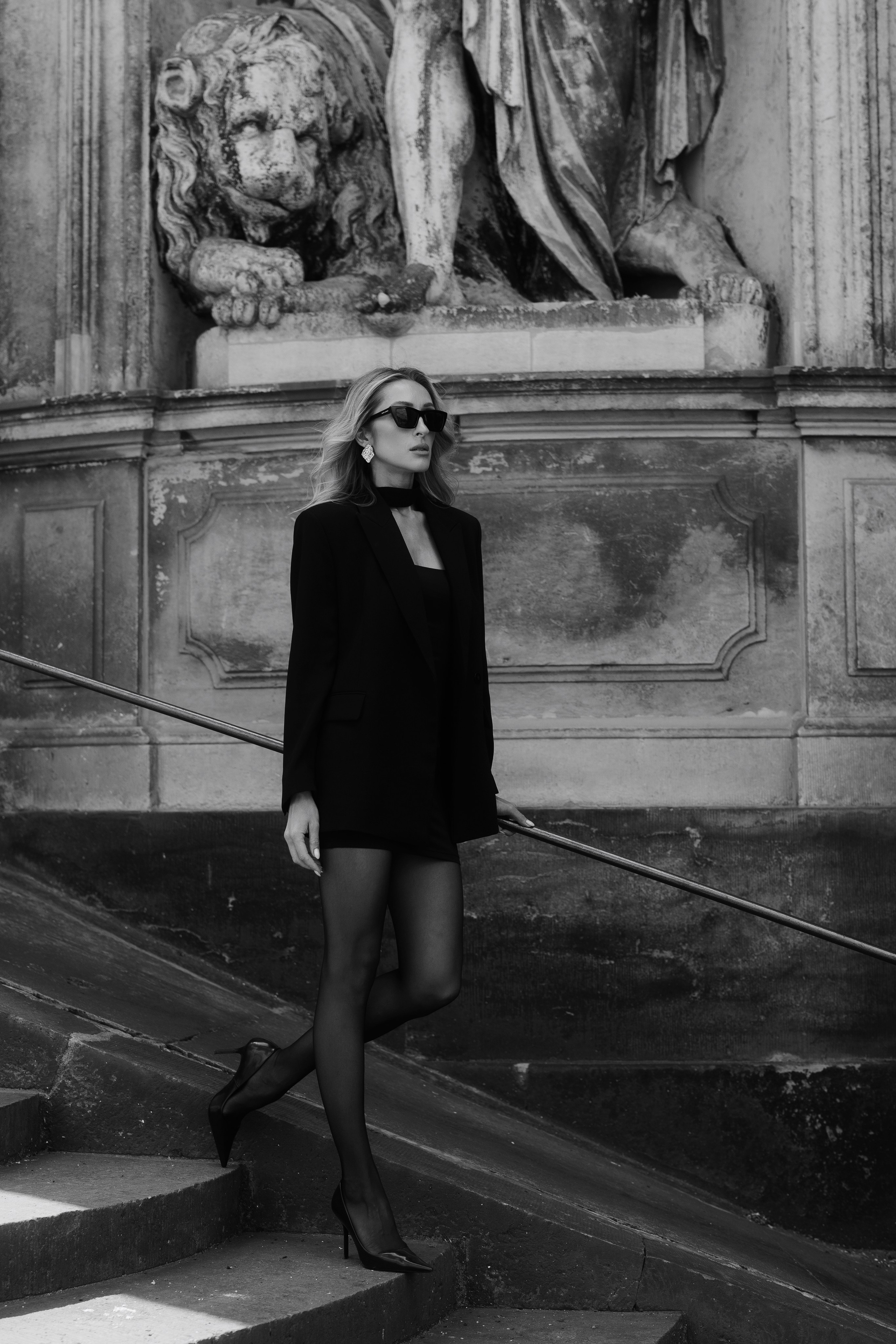 Black and white editorial portrait of an elegant woman in a black blazer and sunglasses at a historic palace in Dresden, Germany. Fine art female portrait photography by photographer based in Leipzig and Wurzen. Чёрно-белый редакционный портрет элегантной девушки в чёрном жакете и солнцезащитных очках на фоне исторической архитектуры Дрездена, Германия. Художественная женская портретная фотография фотографа из Лейпцига и Вурцена.