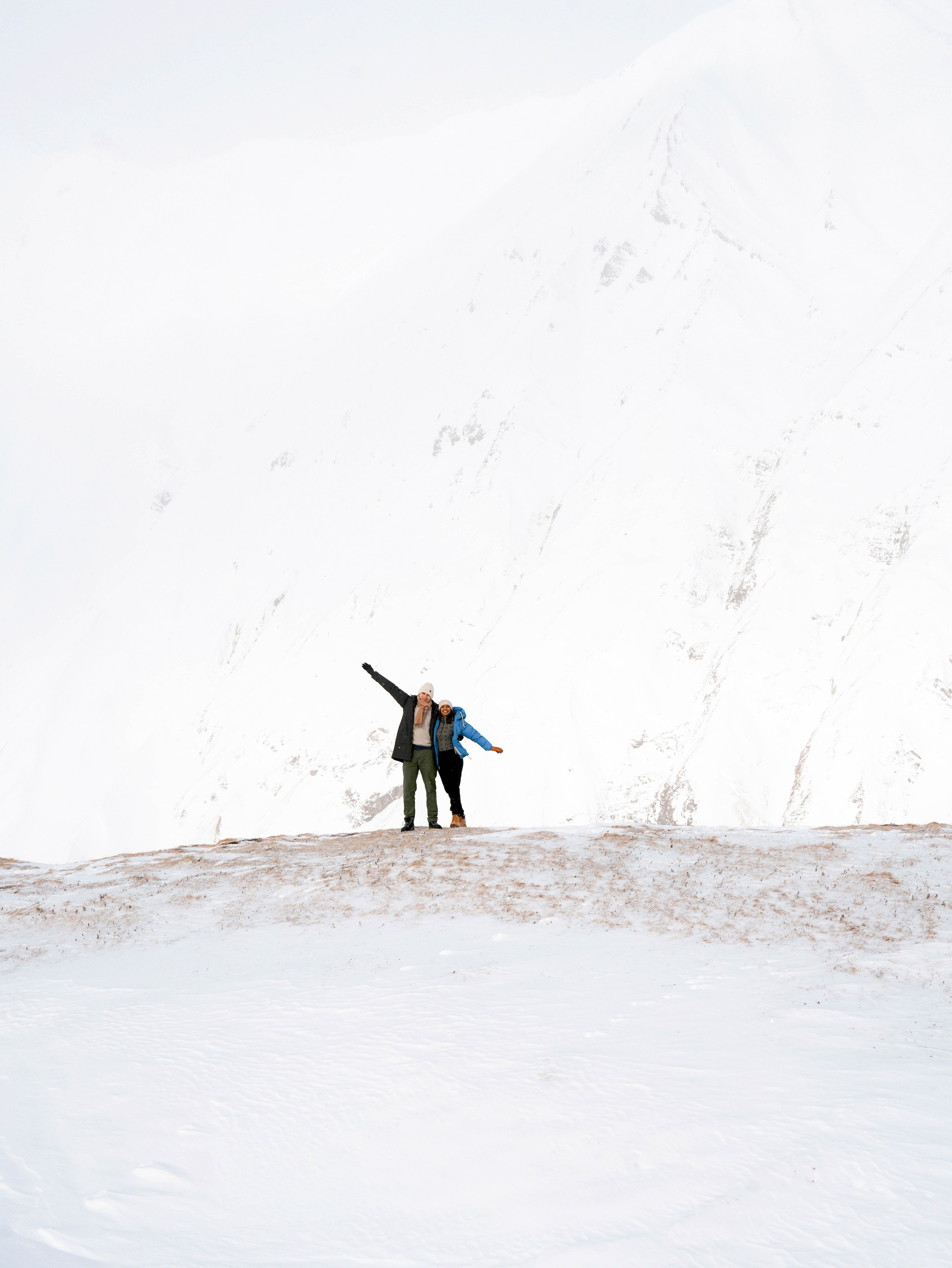 Couple standing on ridge with wide snowy landscape