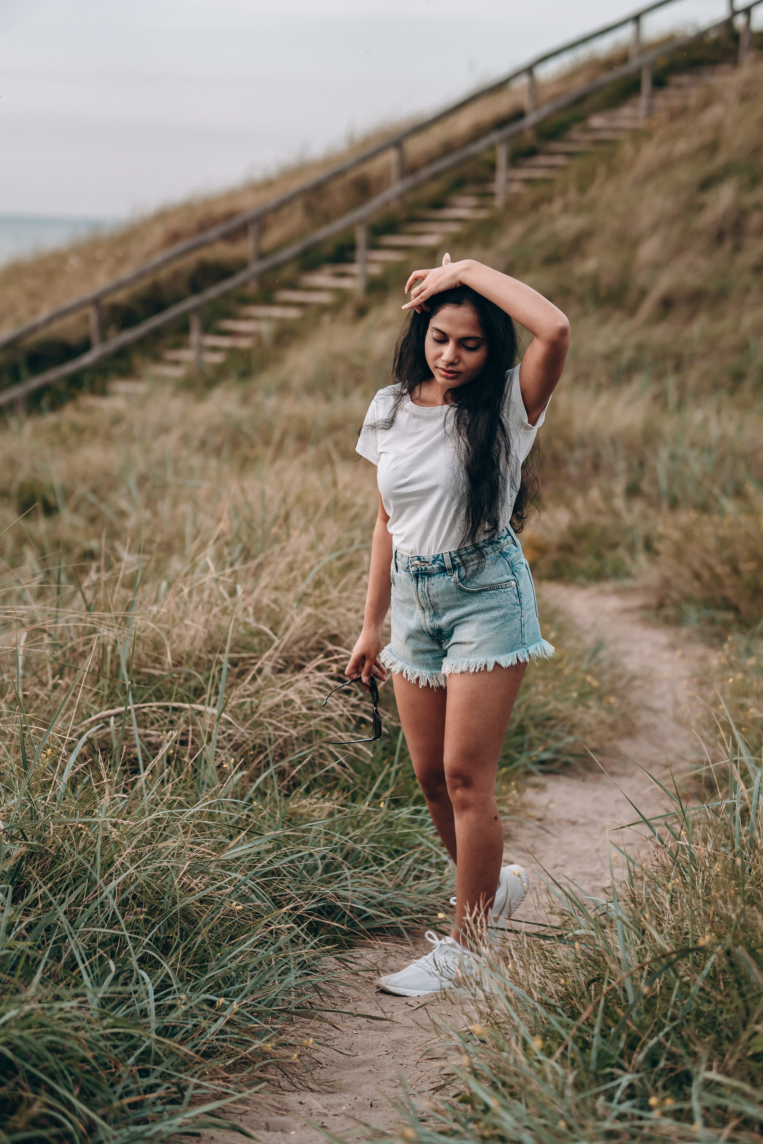 Woman walking along a narrow path close to the beach