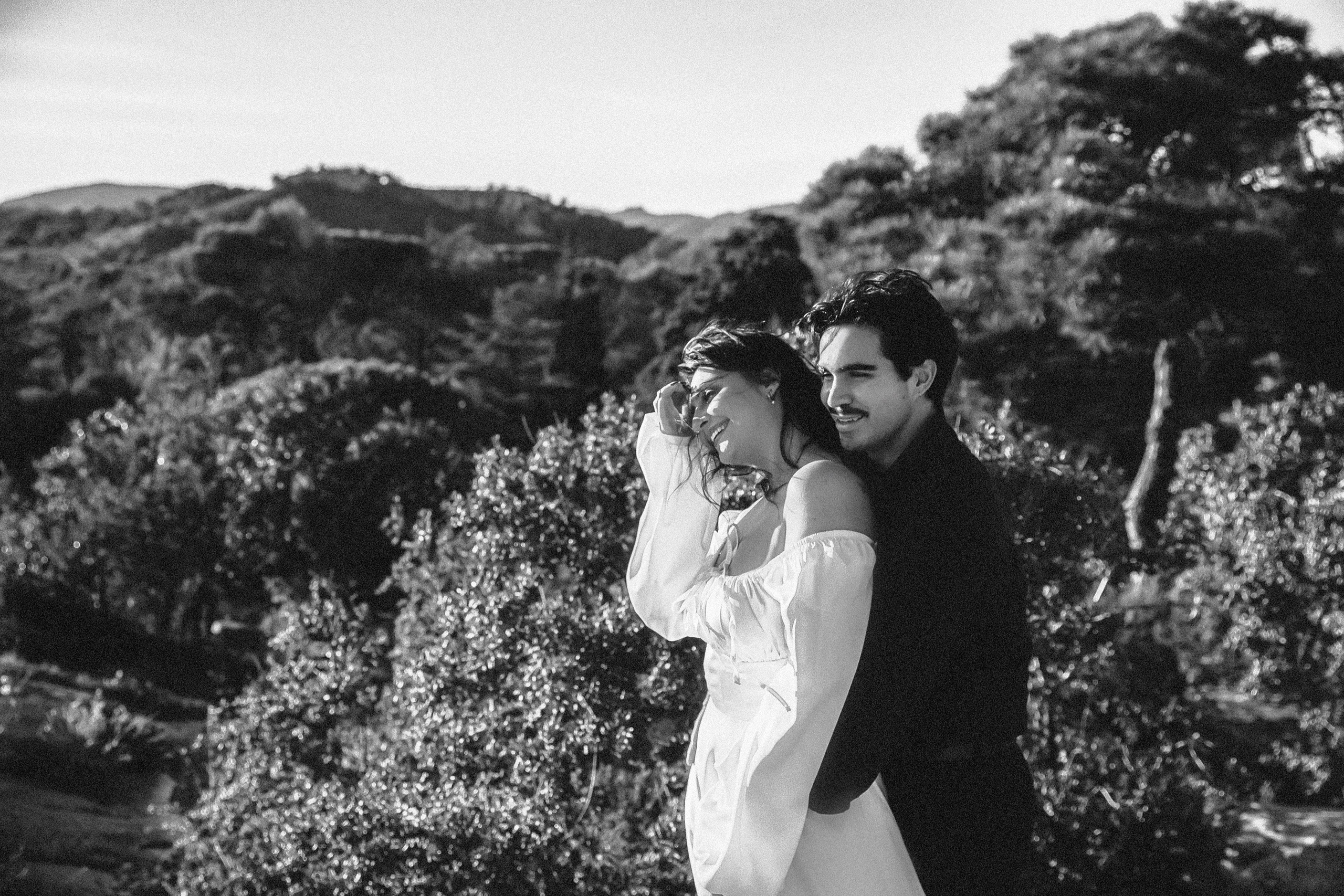 Bride and groom walking together through rocky terrain during a secluded mountain destination wedding in Barcelona, Spain. The black and white elopement portrait emphasizes emotion, texture, and timeless romance.