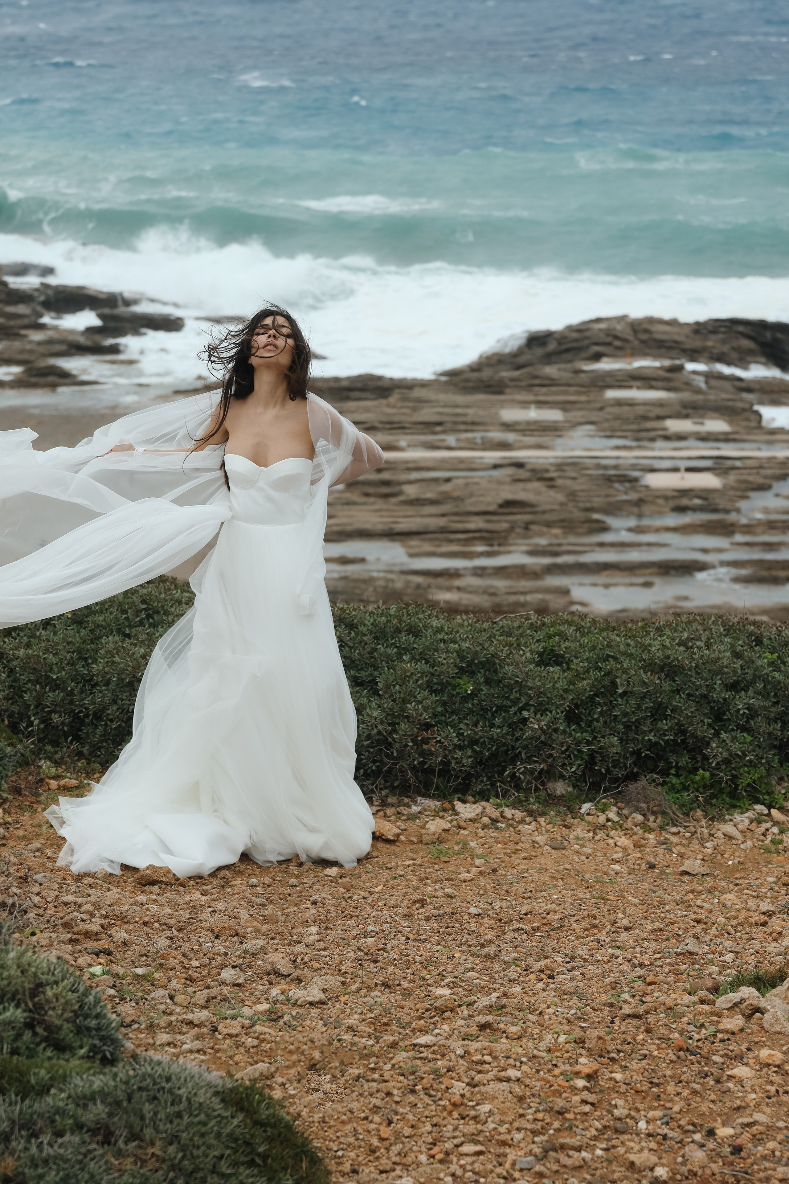 An art photo shoot of a girl in a wedding dress on the windy Kalithea beach in Rhodes, Greece