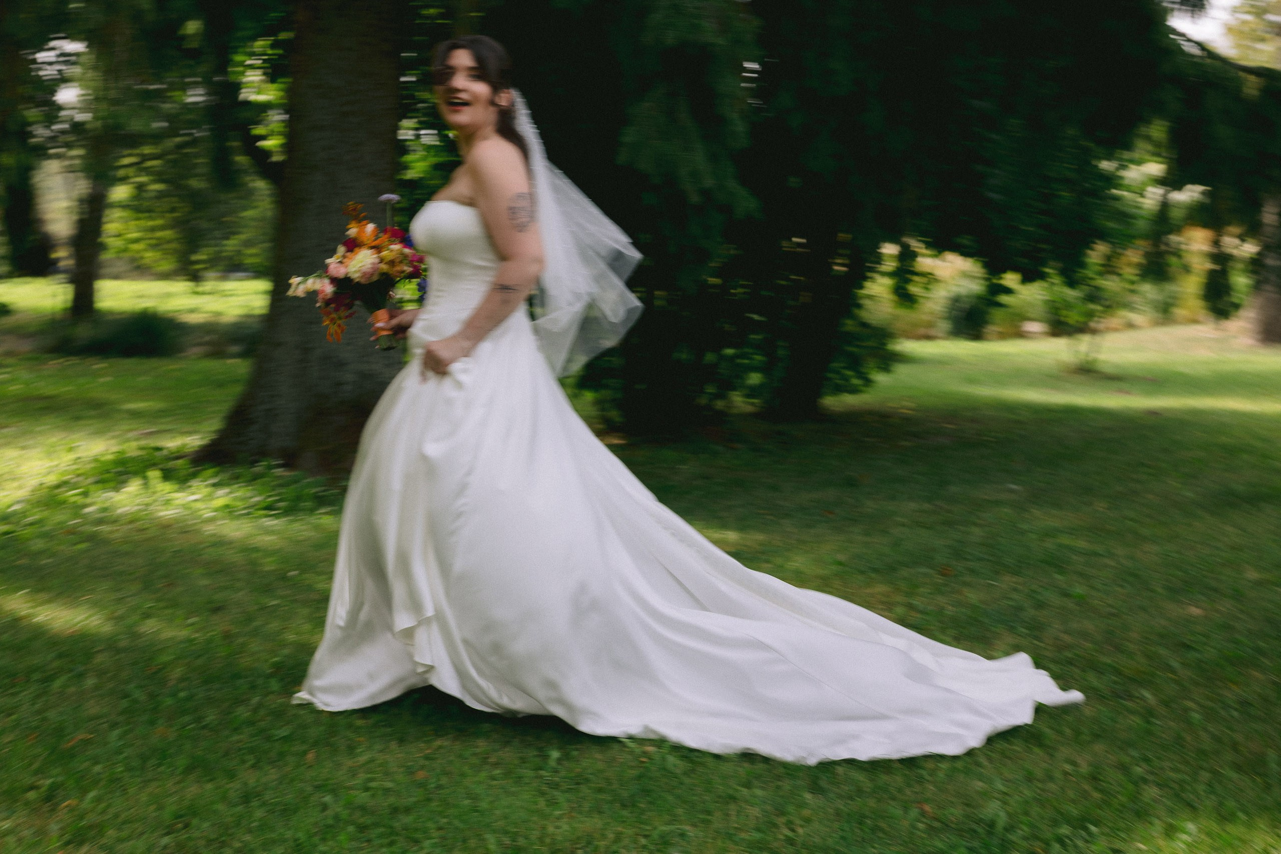 Elegants pilna auguma portrets ar līgavu un viņas kleitas šleifu pļavā.