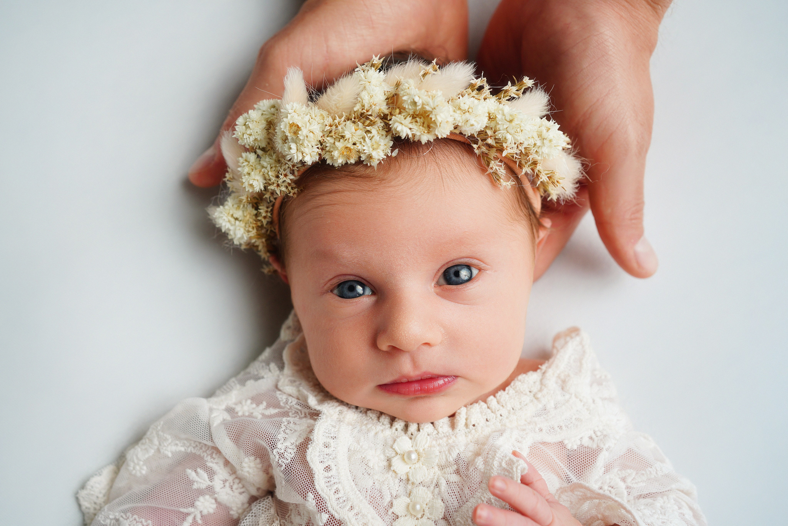 Mama hält Neugeborenes sanft im Fotostudio