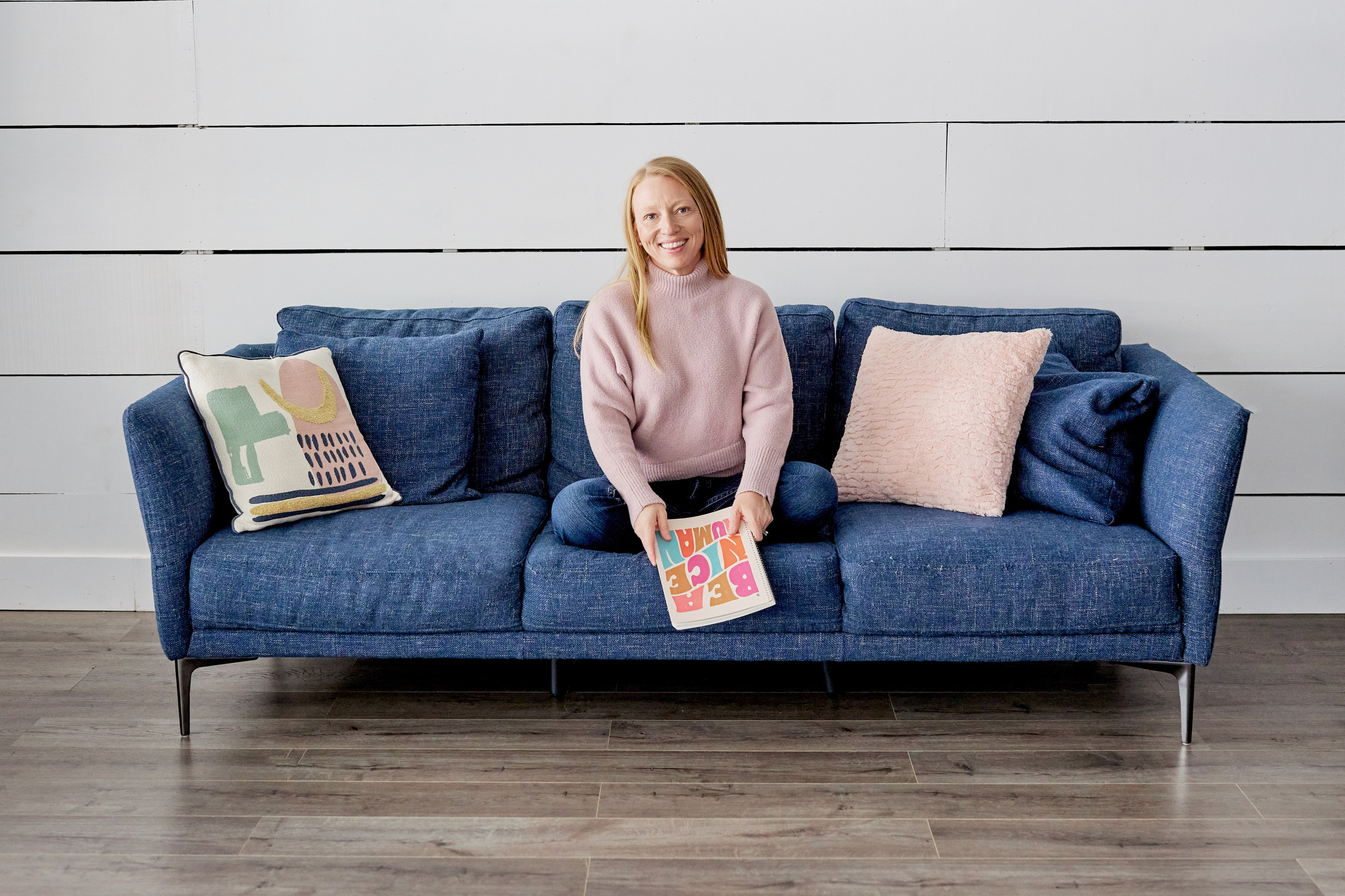 woman sitting on blue couch holding journal 