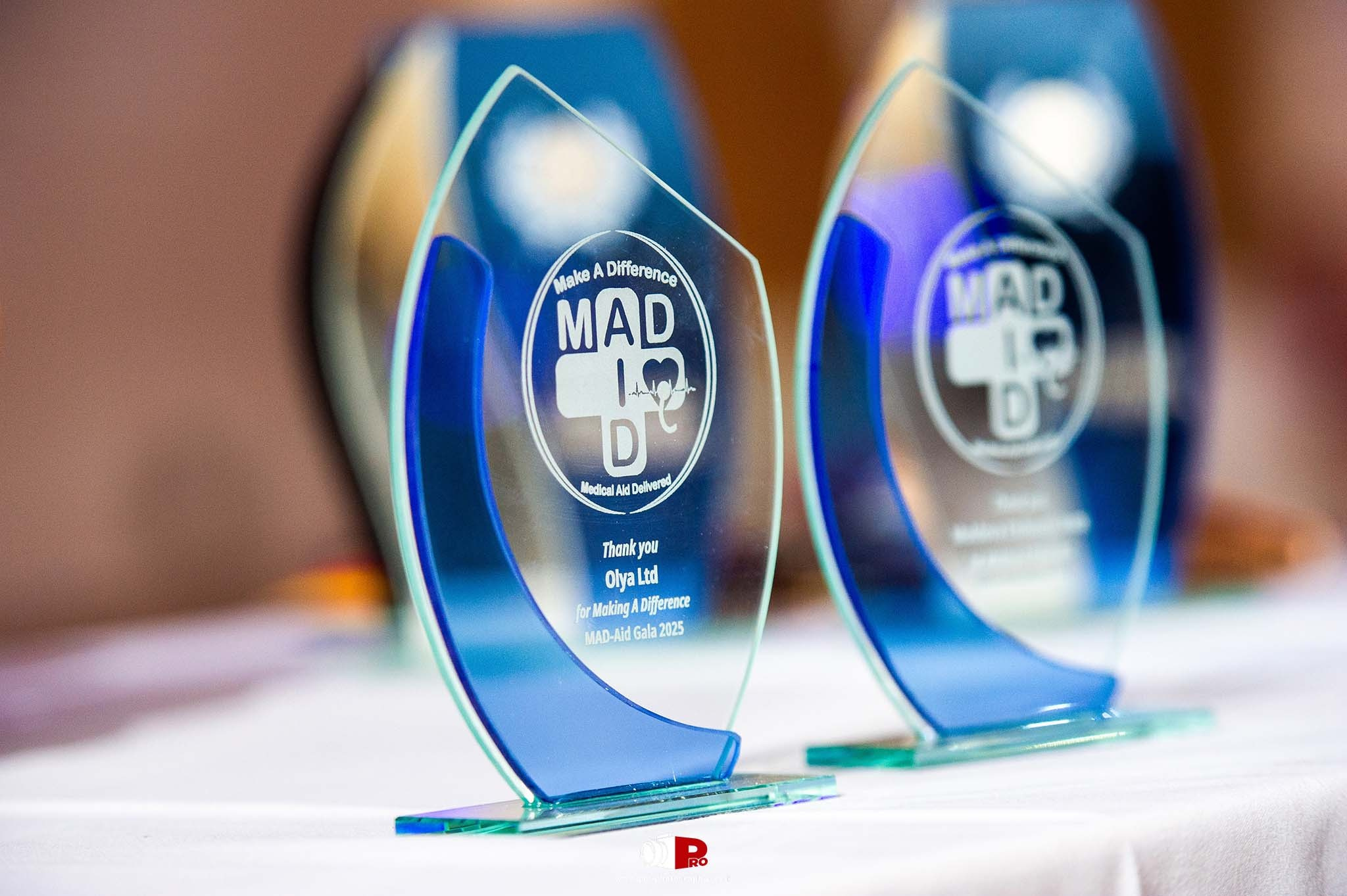 Close-up of sleek blue MAD-Aid award trophies on a white tablecloth, symbolizing recognition for positive contributions.