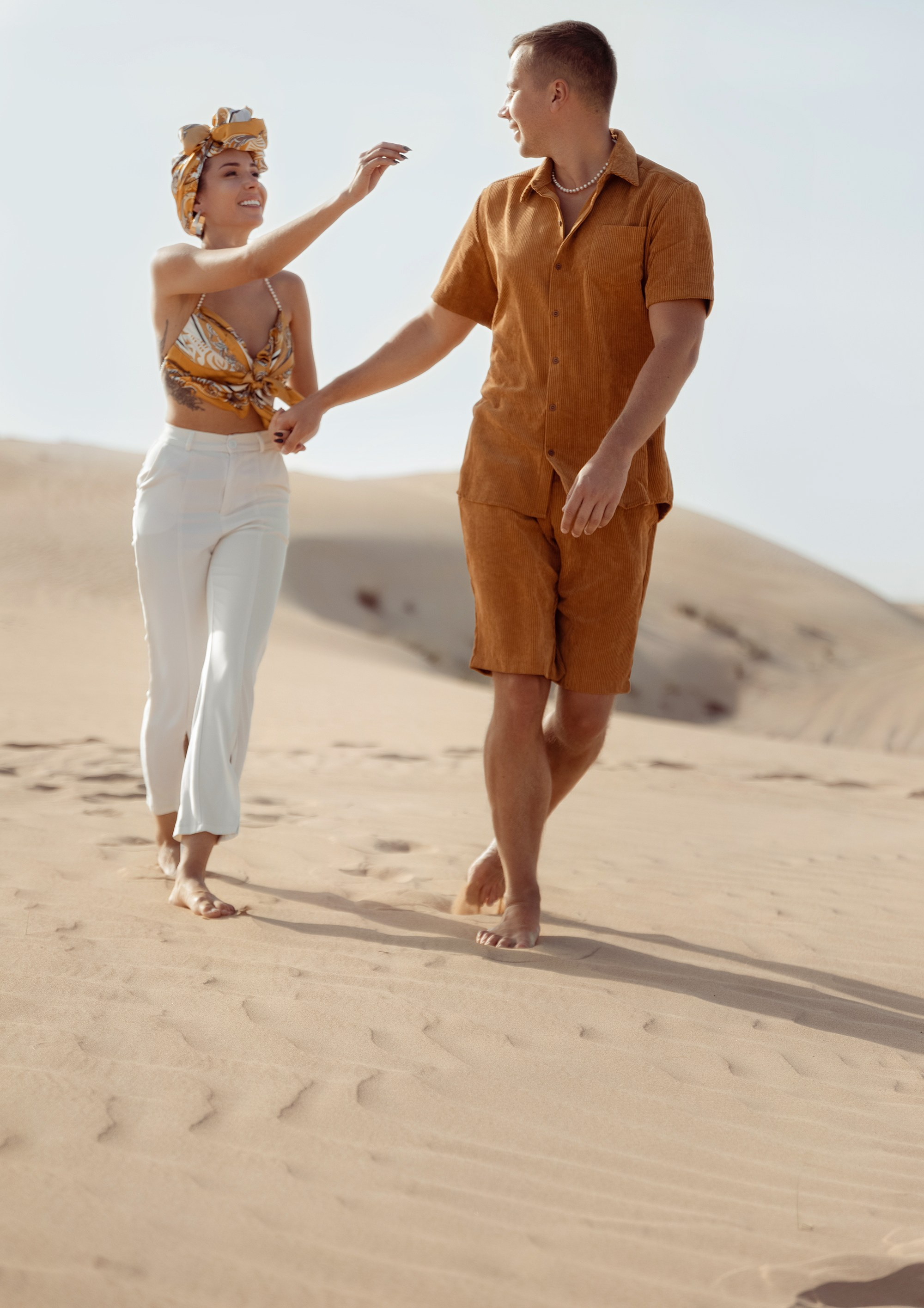 A couple shares a spontaneous, joyful moment in the desert, their embrace reflecting the warmth and beauty of the surrounding nature. Dubai, United Arab Emirates
