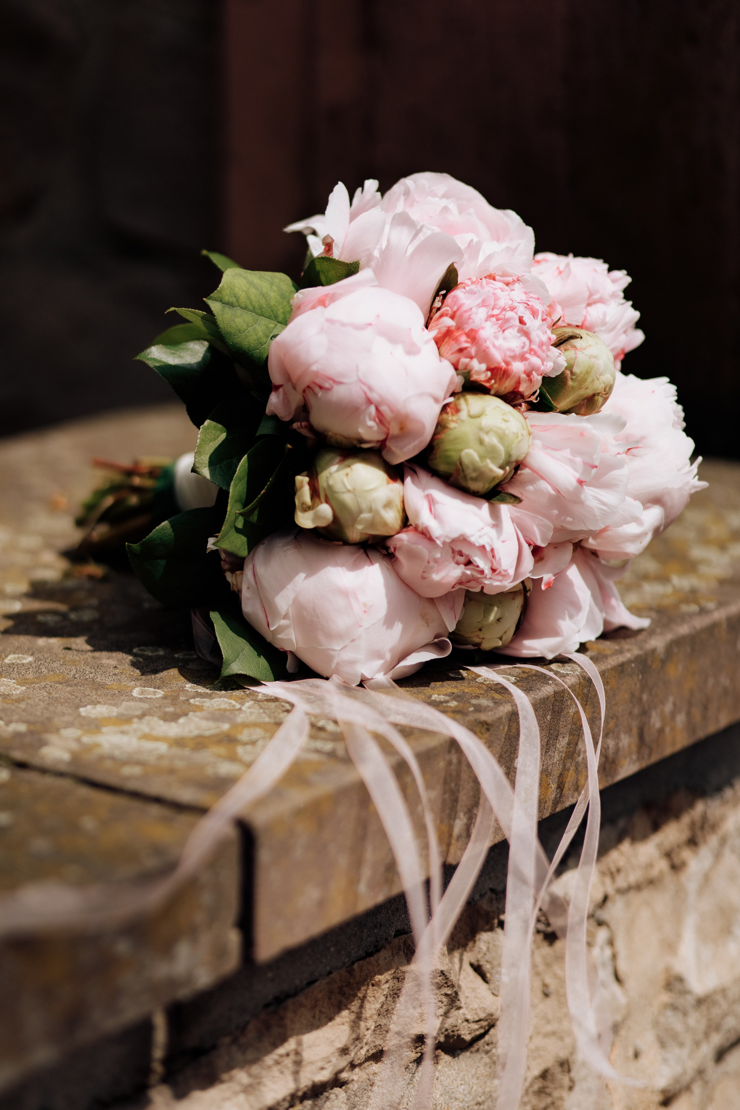 Der Brautstrauß liegt auf einer steinernen Mauer.