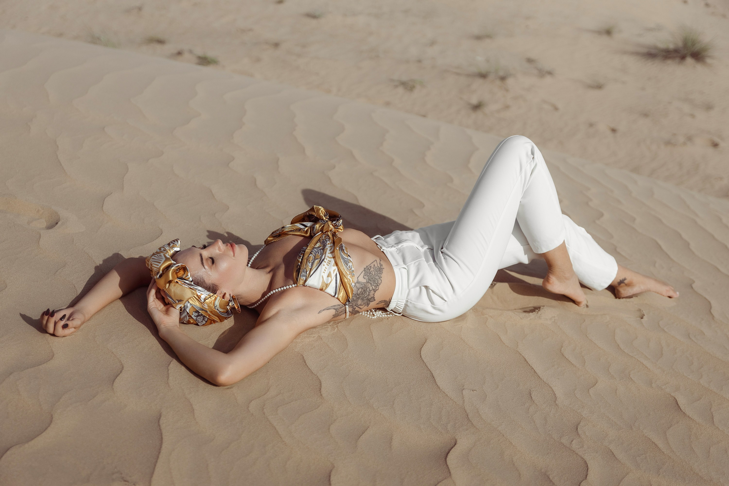 A mesmerizing portrait of a woman in the desert, her presence commanding attention as the sun casts a warm glow over the sandy horizon. Dubai, United Arab Emirates