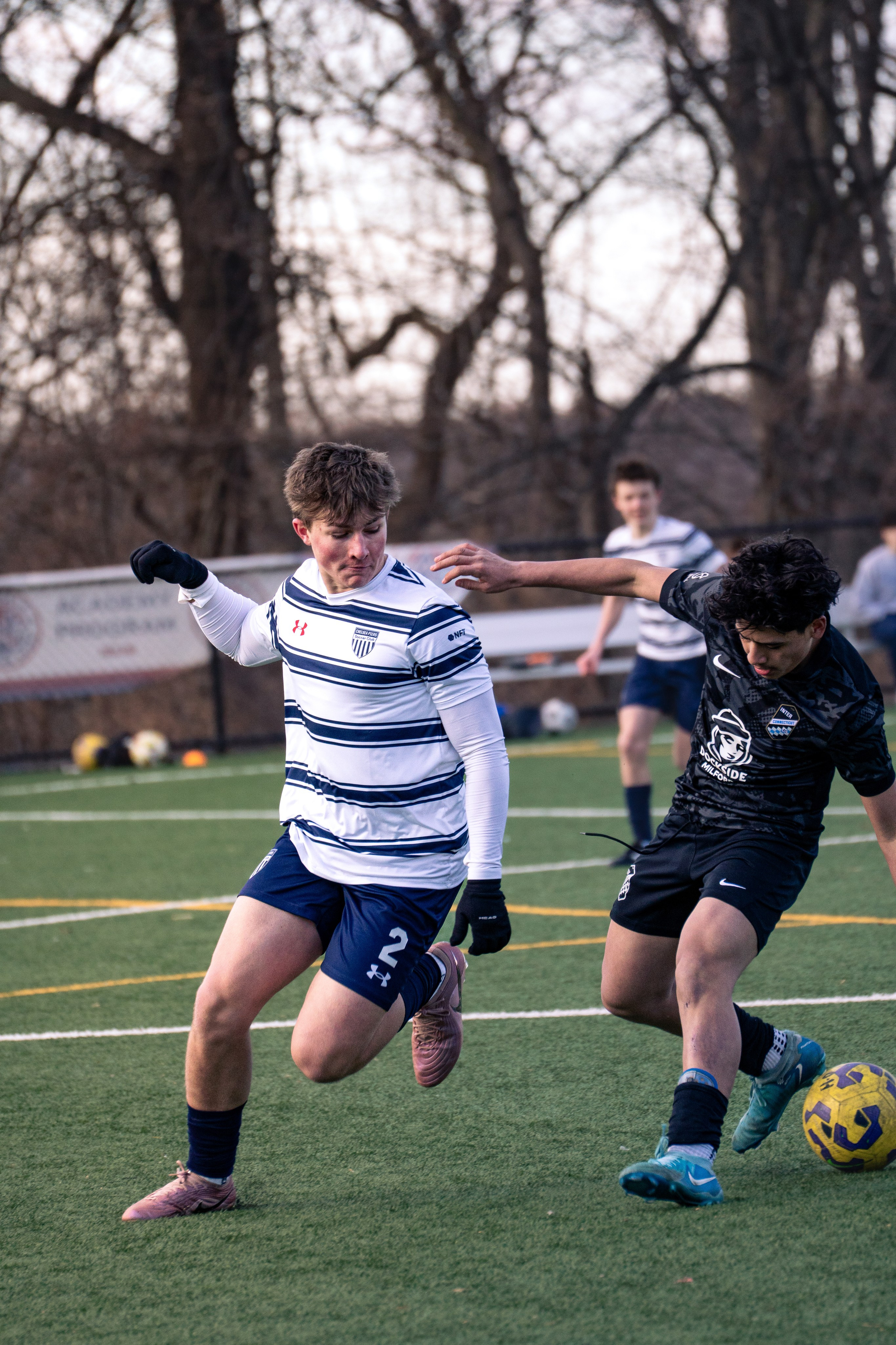 High school soccer attacker losing control of the ball as a defender moves in behind him ready to win possession.