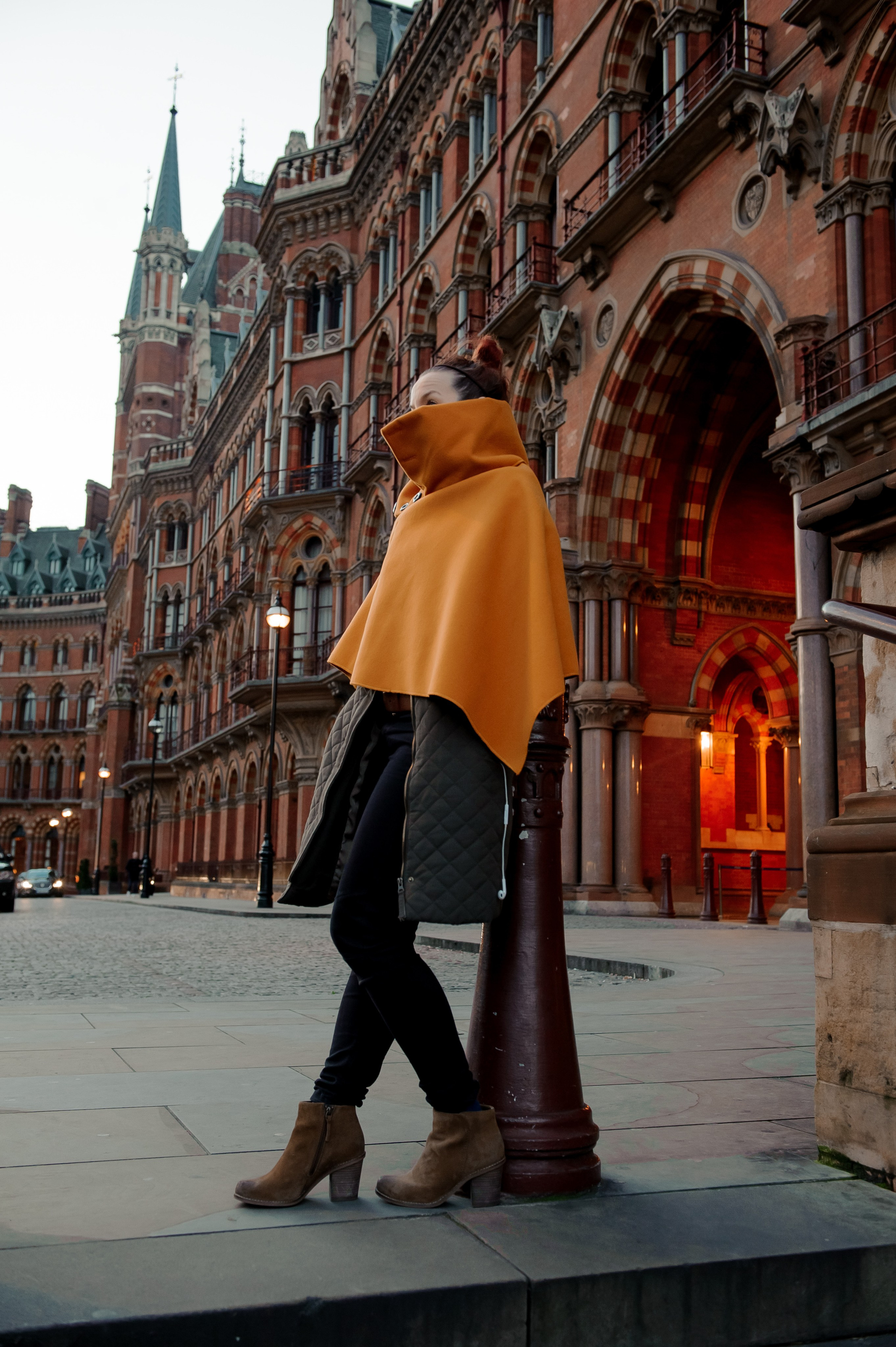 A woman in an orange cape stands outside the Renaissance Hotel in London.