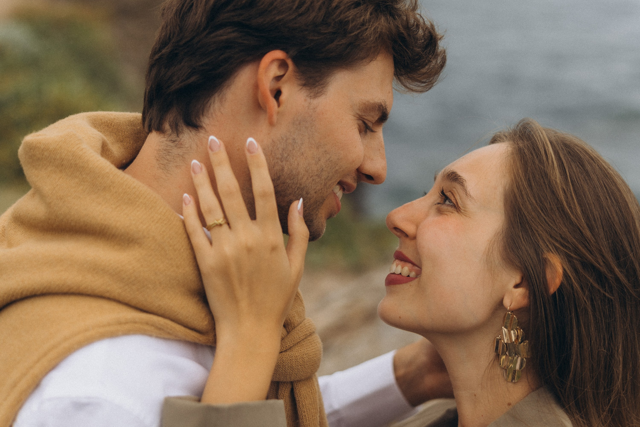 Beautiful engagement moment by the ocean in Madeira, Portugal, as one partner kneels to propose while waves crash in the background