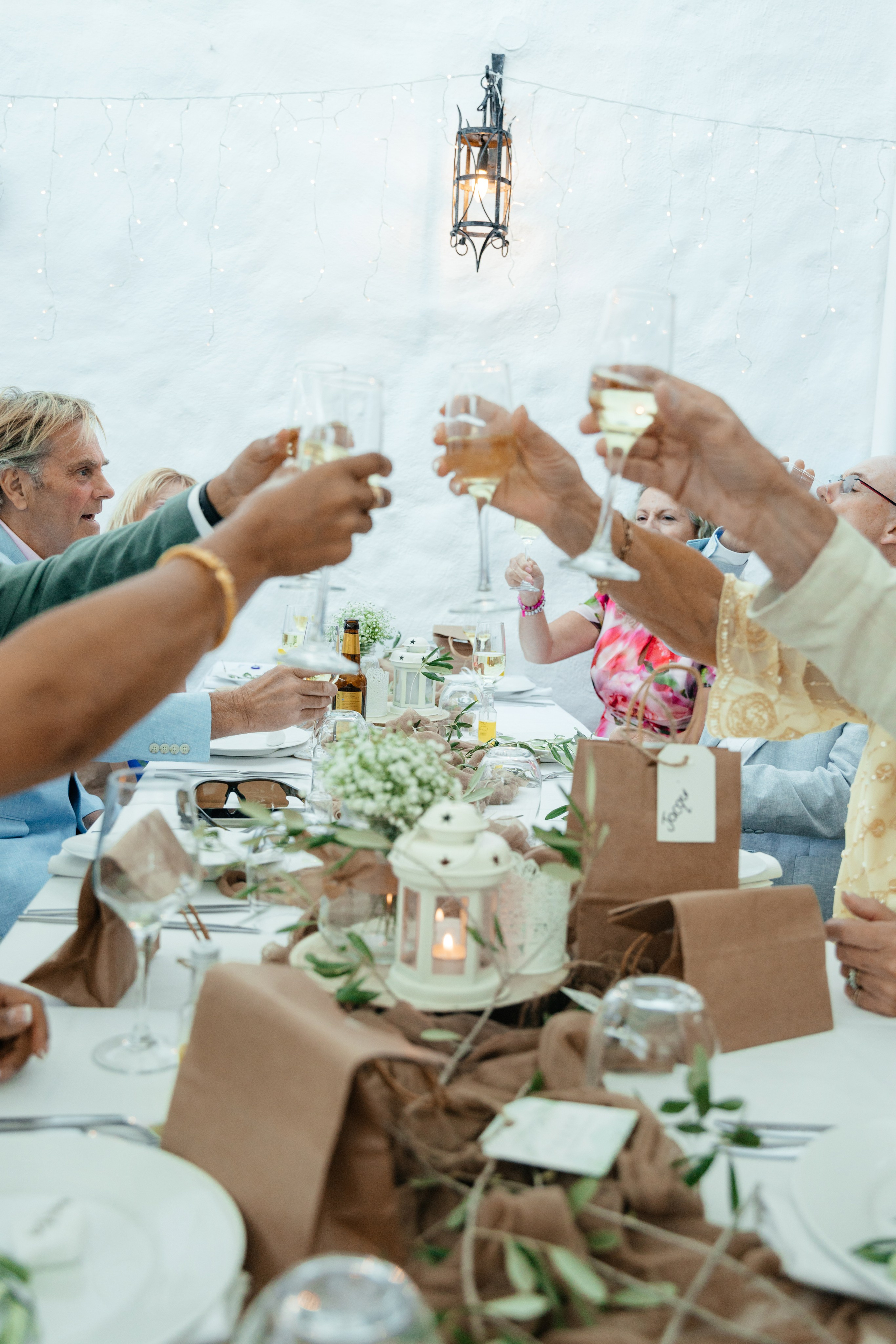 guests clinking glasses filled with local Greek wine during a festive wedding celebration in Lindos, Rhodes, Greece