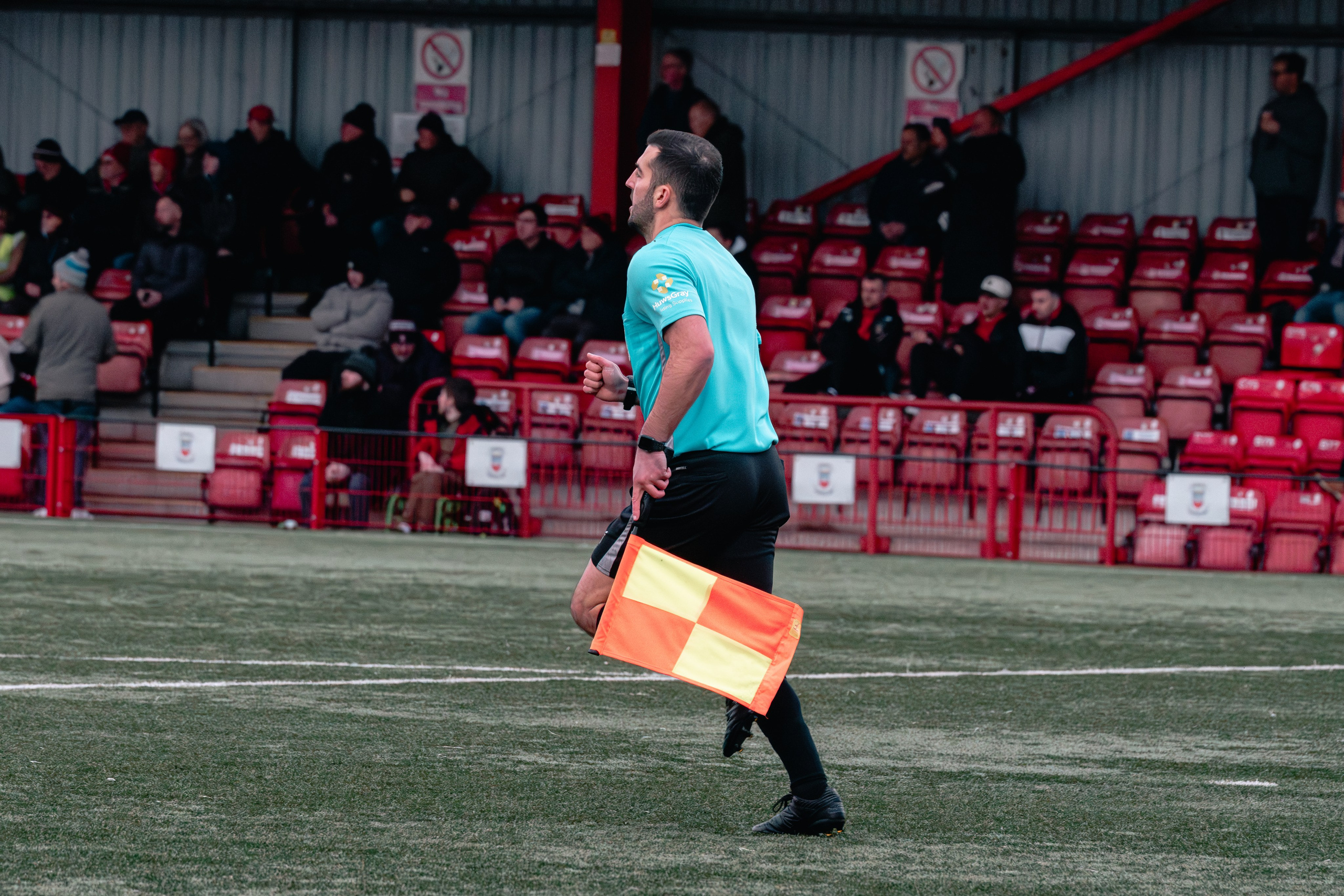 Assistant referee James Hooper runs along the touchline holding a flag during the match.