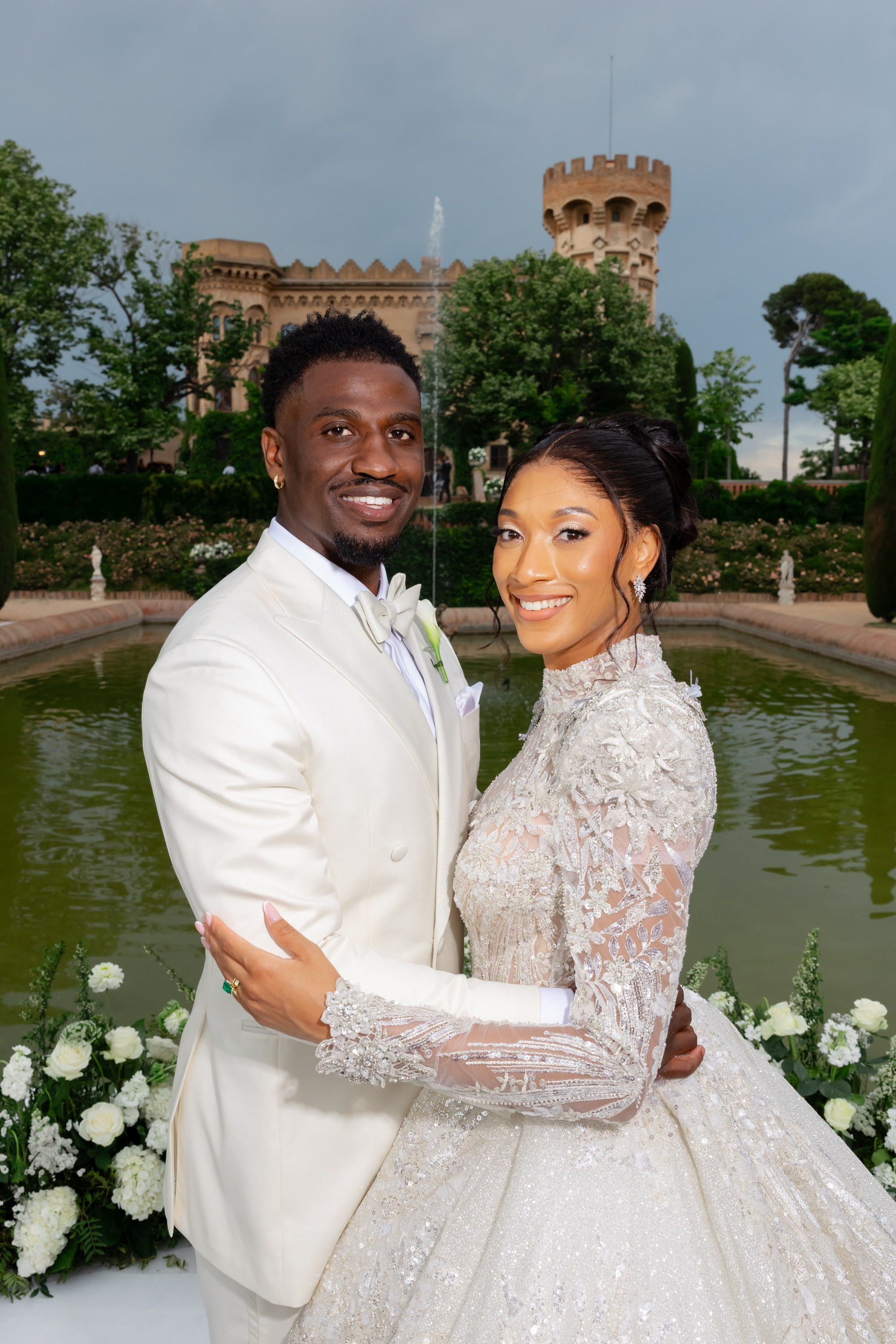 dark skinned bride and groom hugging with a Spanish castle on the background