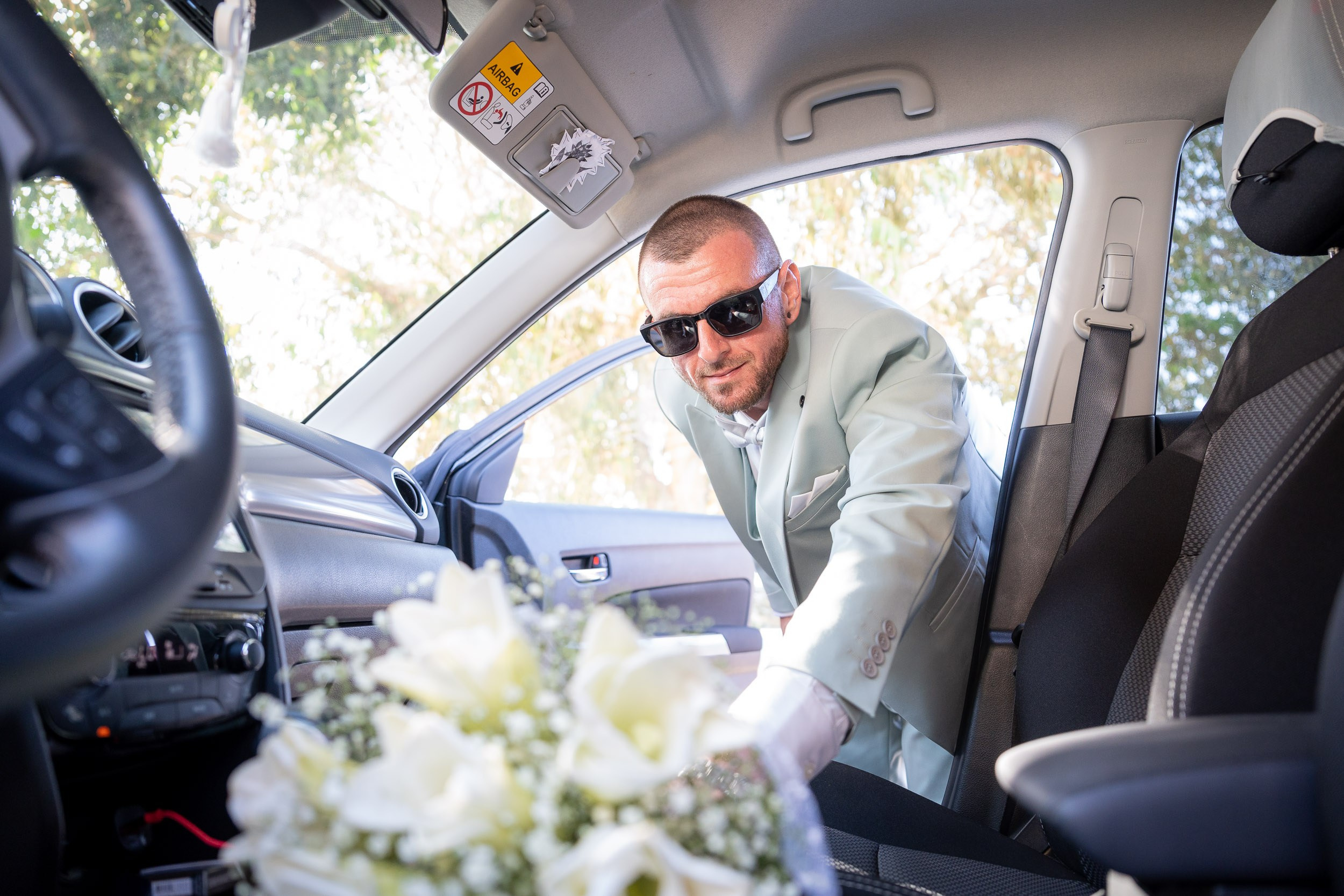 Matan takes the white wedding bouquet from a car