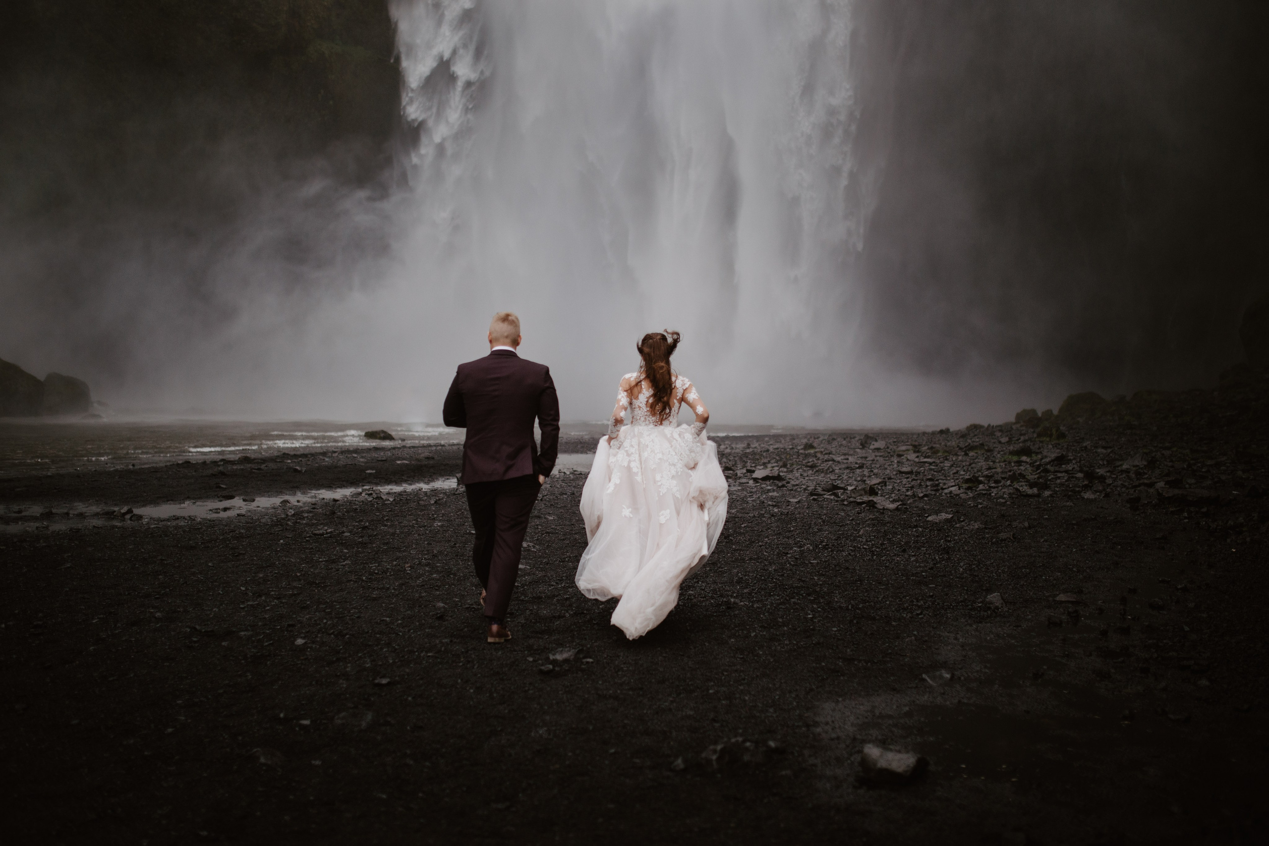 Love in the wild—couple sharing a quiet moment in front of a majestic Icelandic waterfall.
