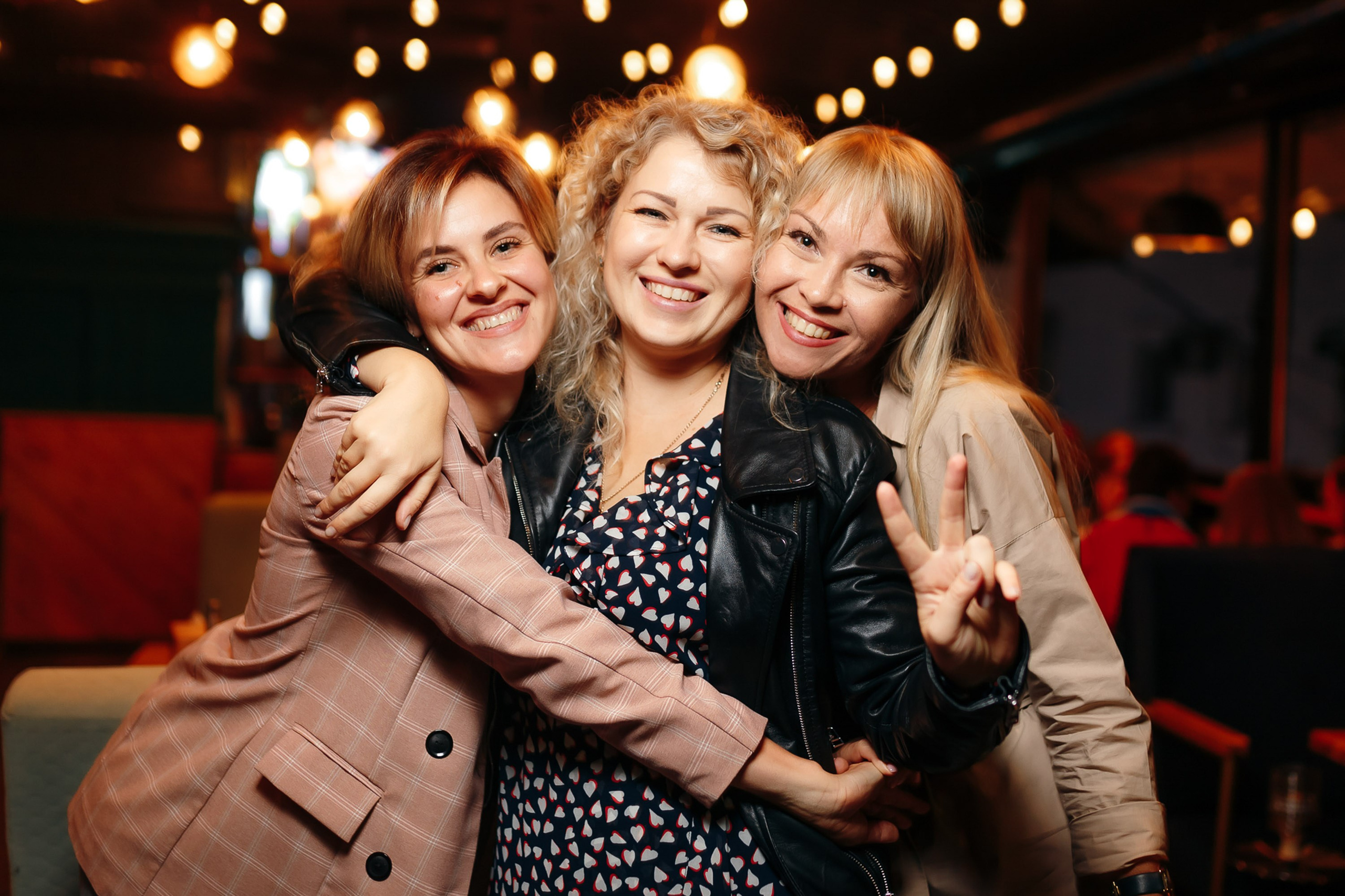 Three women hugging and smiling at a party