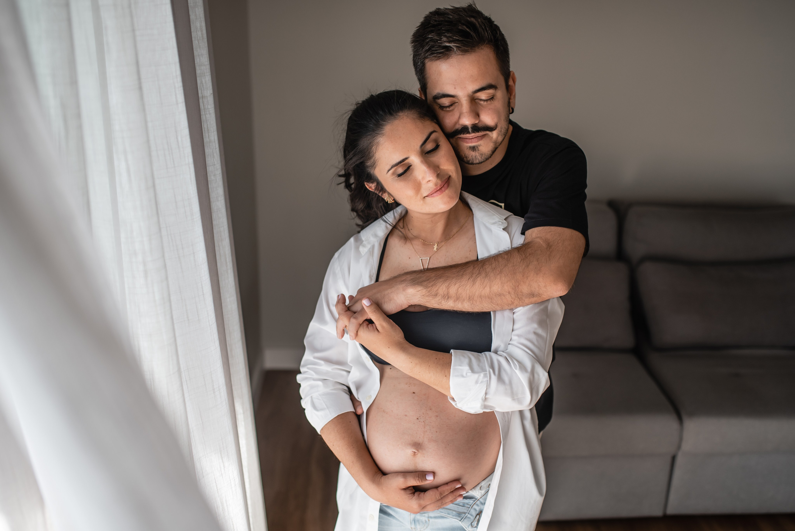 Ensaio gestante de casal em ambiente interno, luz natural e conexão emocional em Belo Horizonte