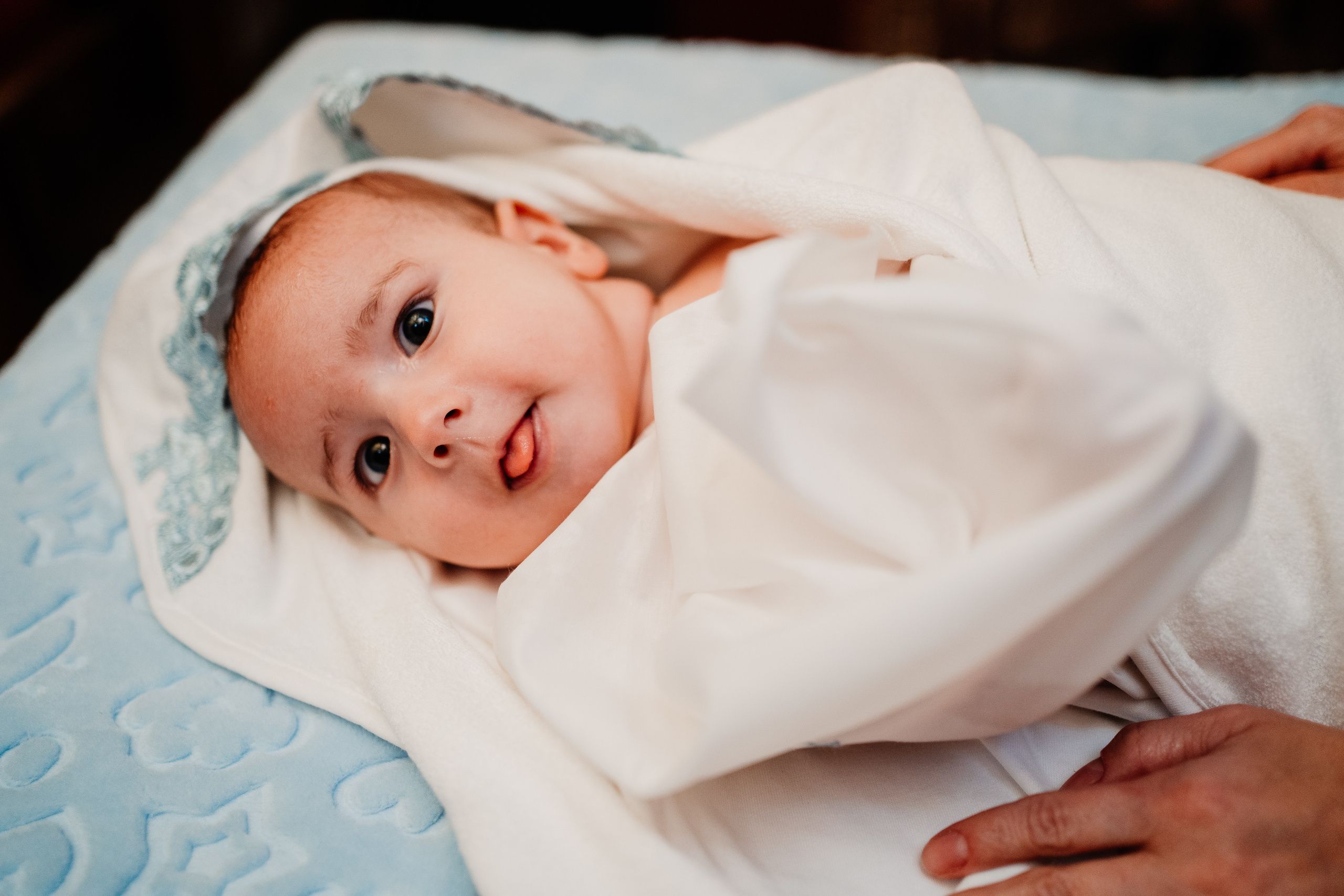 Instantaneu plin de tandrețe dintre părinți și bebeluș în ziua botezului, realizat în Bucuresti. Fotografie profesională de botez, capturând emoțiile autentice ale familiei într-un decor luminos și cald