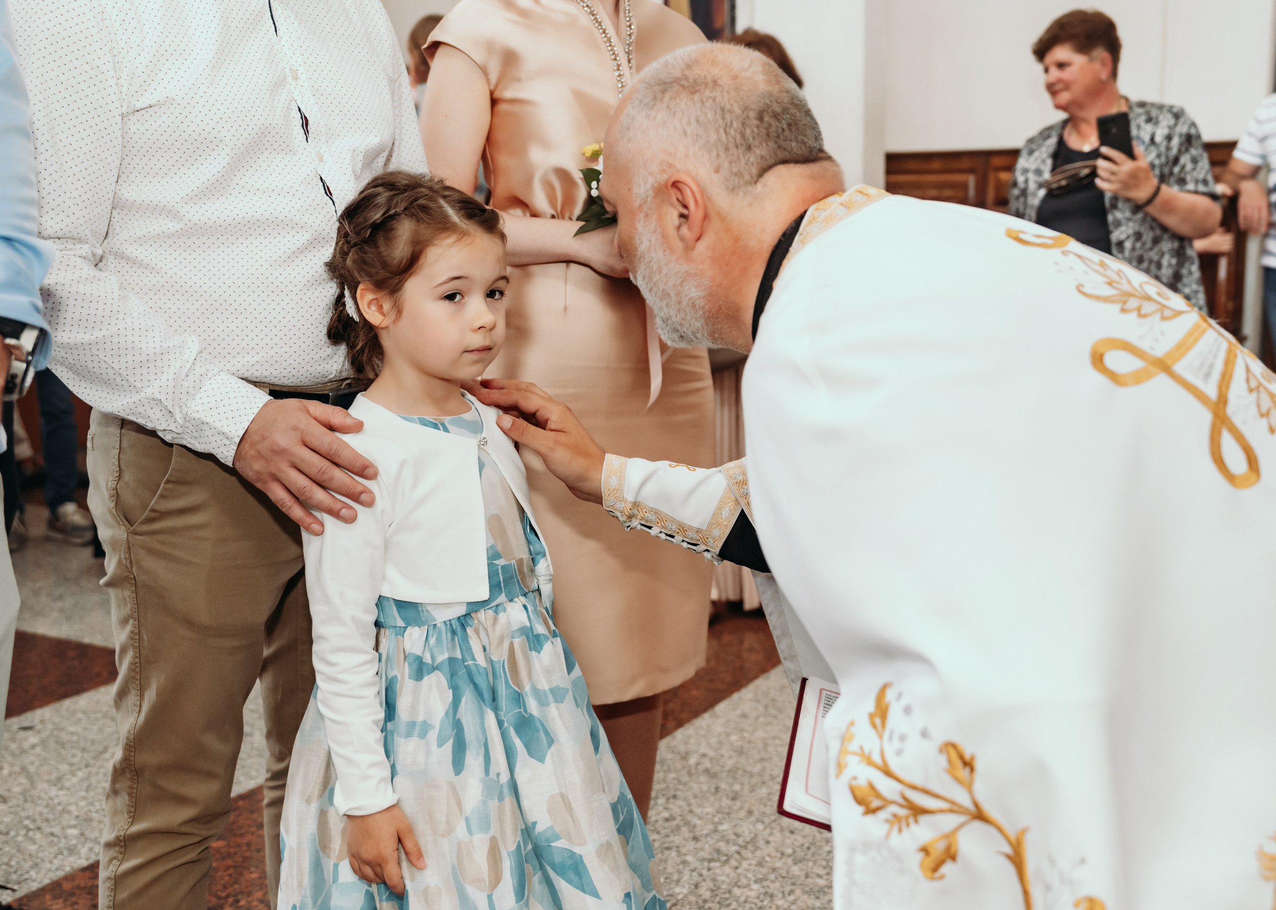 Svestenik pomazuje devojcicu na krstenju