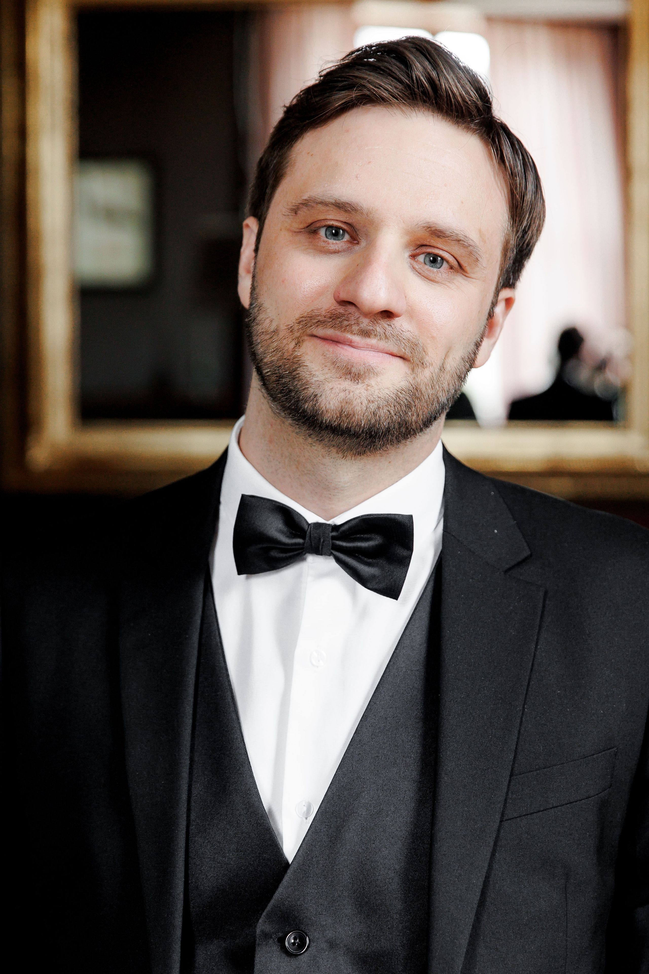 A stylish groom portrait captured in a picturesque French chateau setting showcases elegant wedding attire.