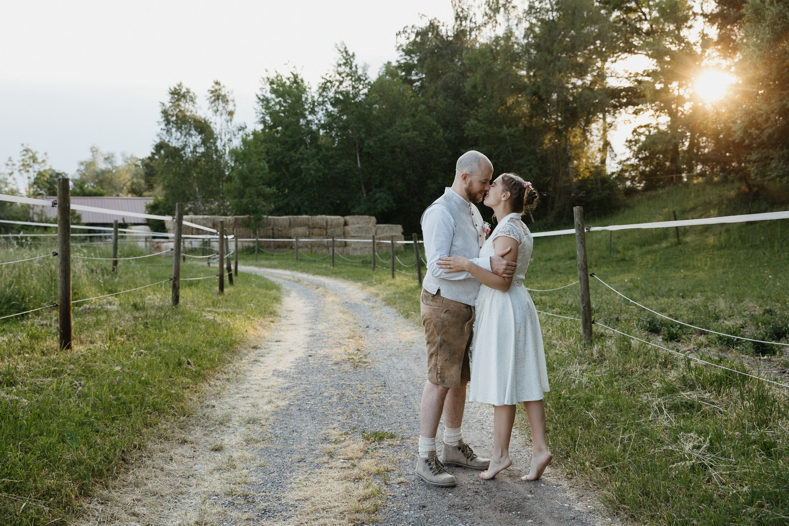Brautpaar küsst sich bei Sonnenuntergang auf Hofweg