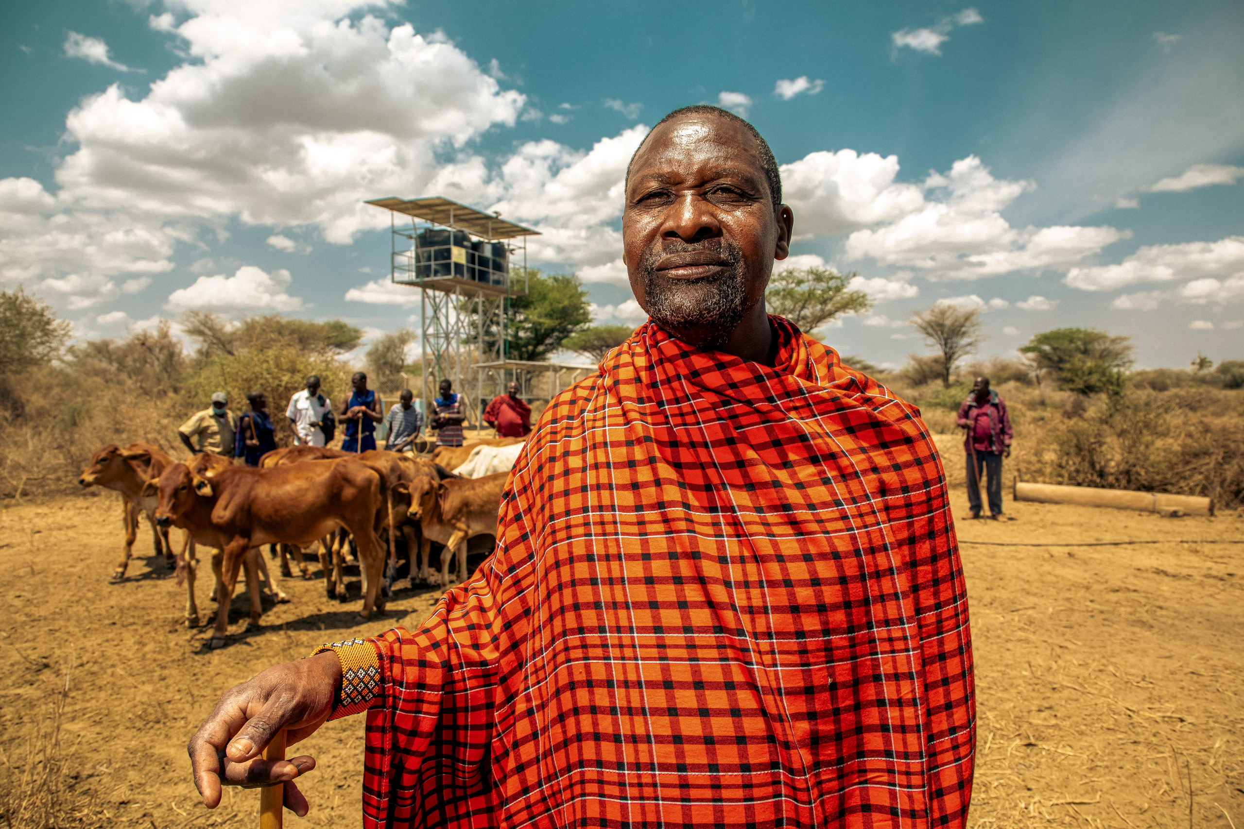 A medium shot of a Maasai cattle owneer poses for a photo at a water point in Oloomaiyana. Documentary photography