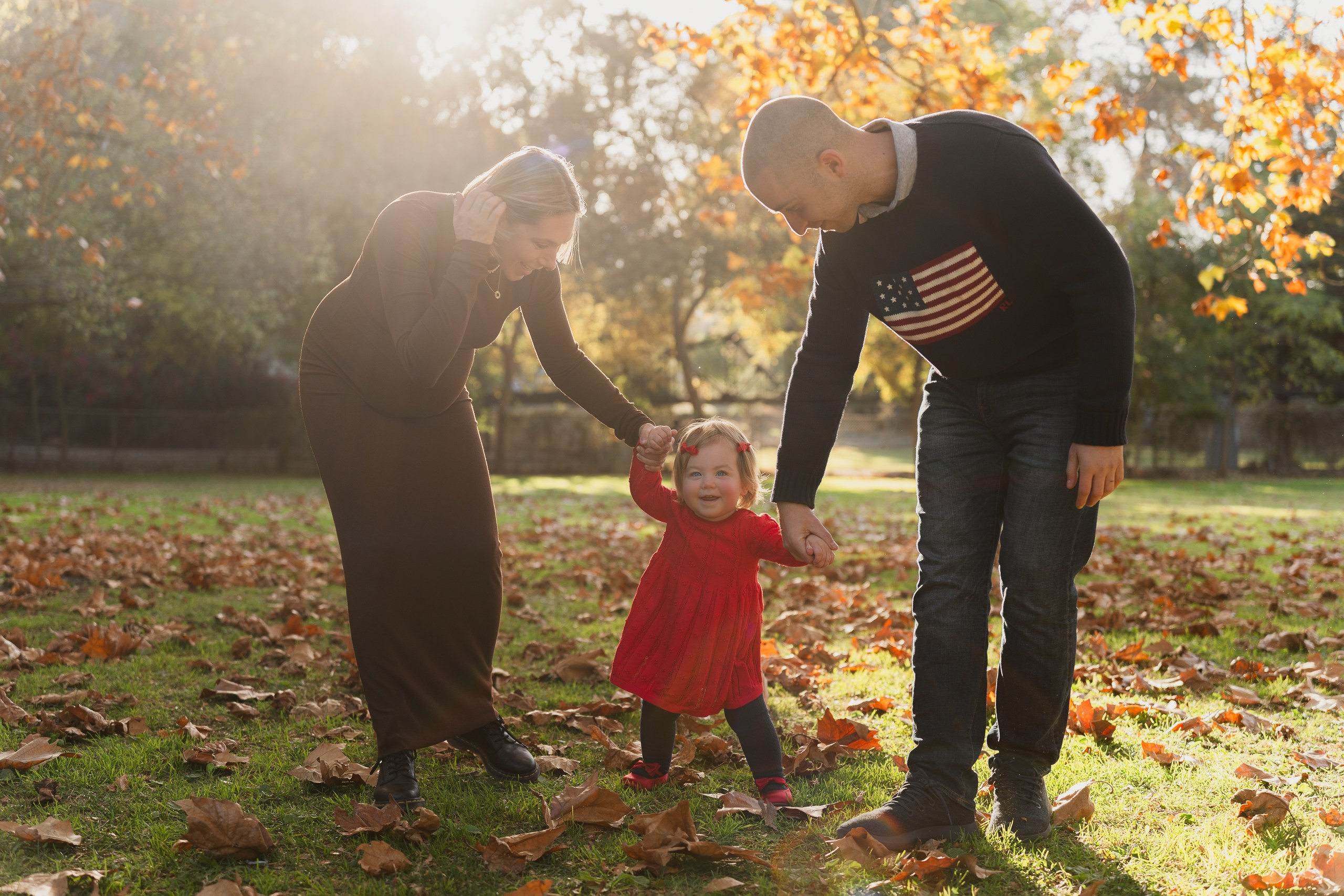 Candid family portrait with parents and their child at sunset