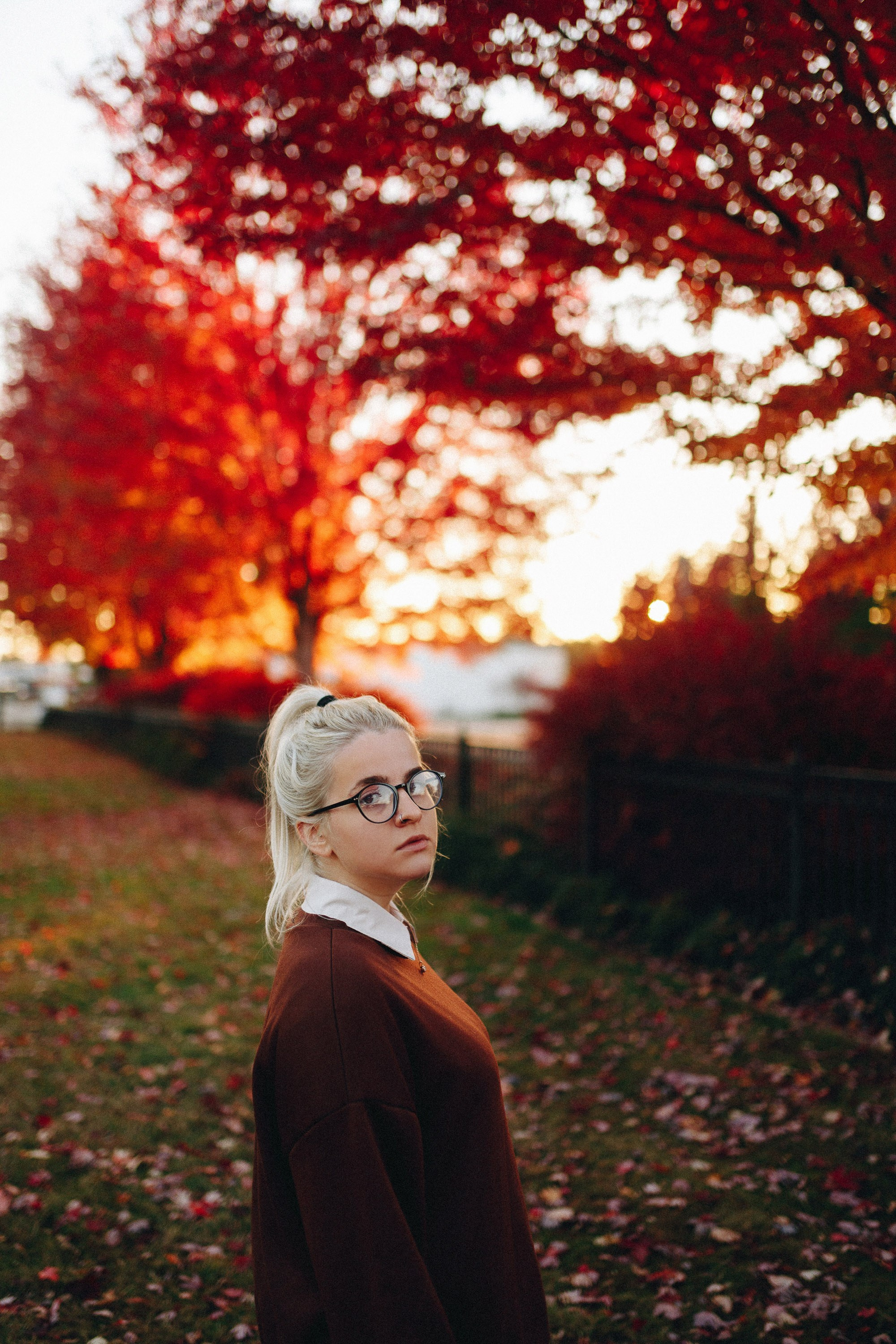 Woman with short blonde hair near autumn tree