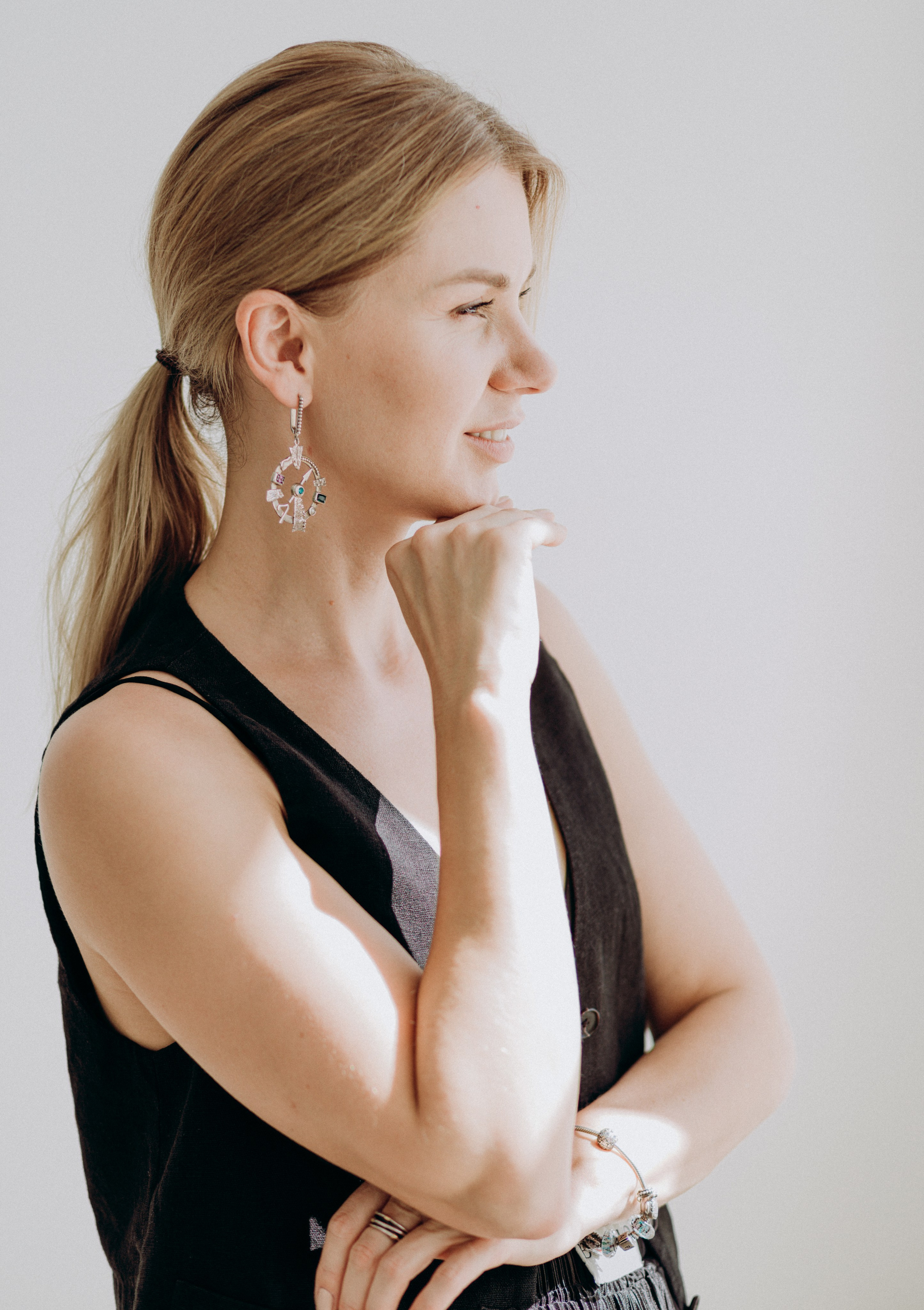 Профессиональный женский портрет, снятый в Валенсии, Испания, с женщиной в профиль в черном топе без рукавов и яркими серьгами — идеально для персонального брендинга, редакционного контента и элегантных портретных фотосессий в Валенсии и по всей Испании.